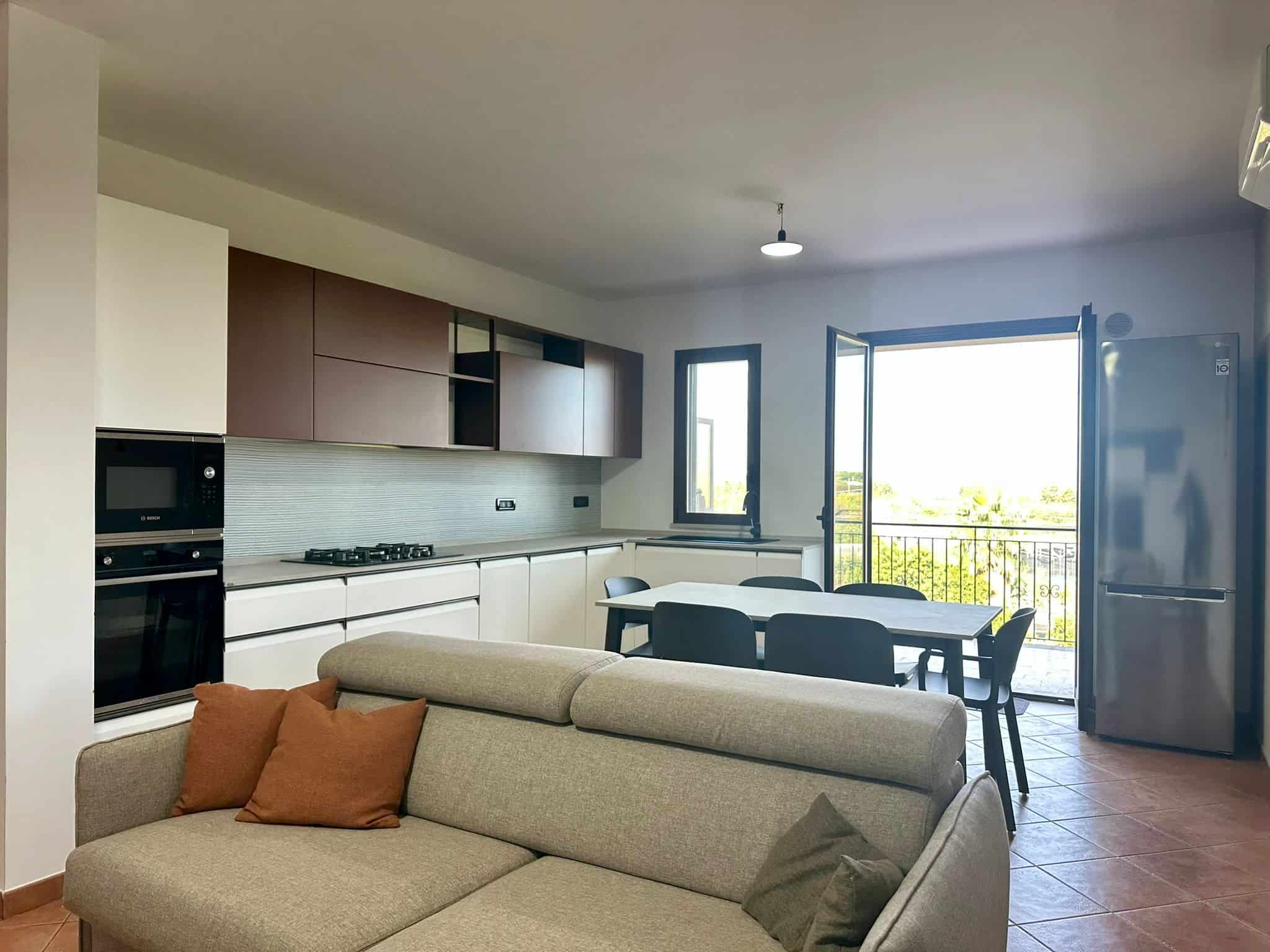Cucina moderna con zona pranzo e balcone, appartamento in affitto, arredato, arredamento contemporaneo, spazio abitativo luminoso e funzionale, interni accoglienti, zona living apertura sulla loggia, ambienti spaziosi, mobilio di design, NextCasa.