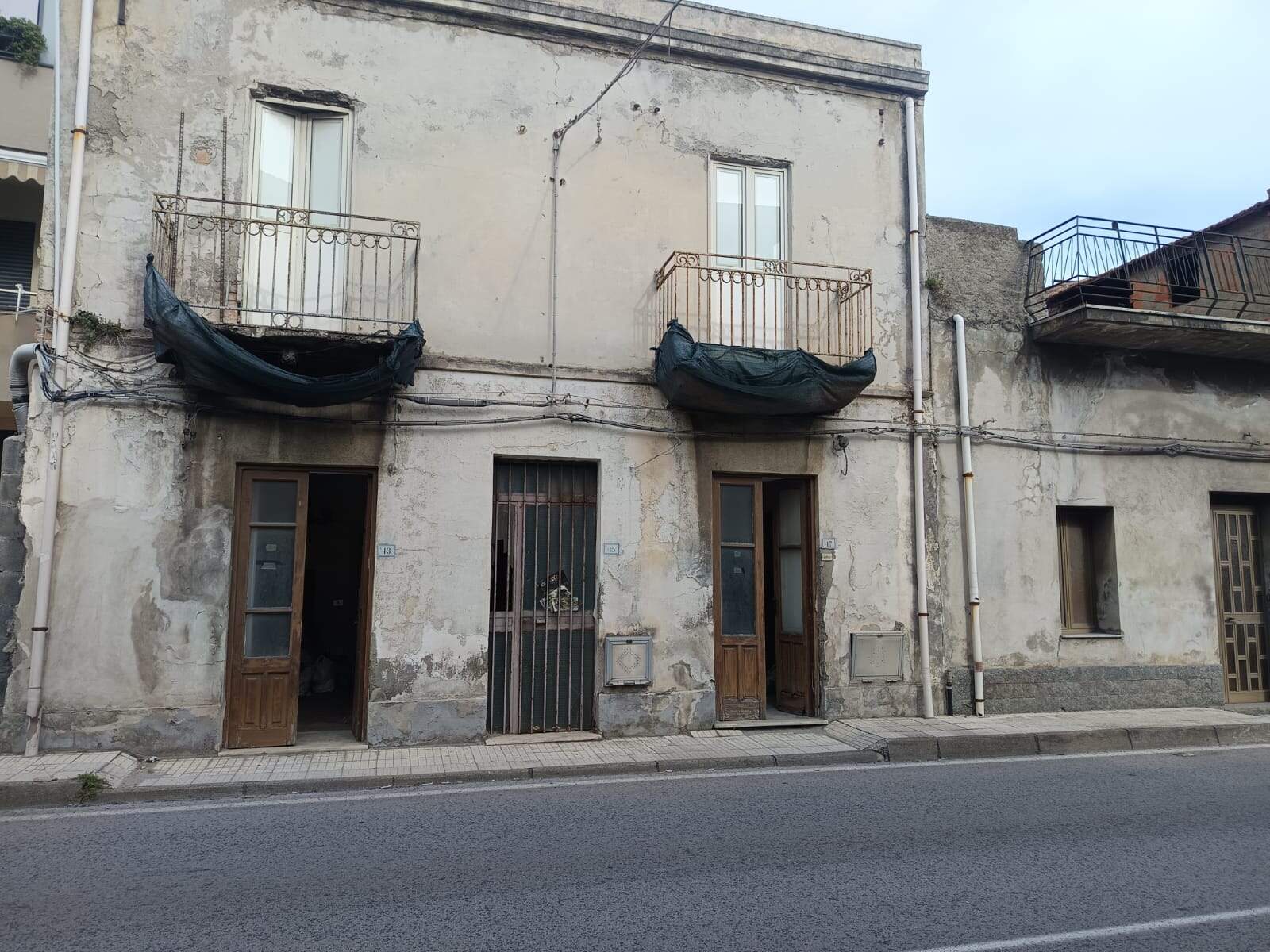 Vecchio edificio residenziale in condizioni di decadenza con pareti esterne usurate e balconi non utilizzabili, situato in strada urbana nel centro storico, da ristrutturare, con potenziale di investimento immobiliare.
