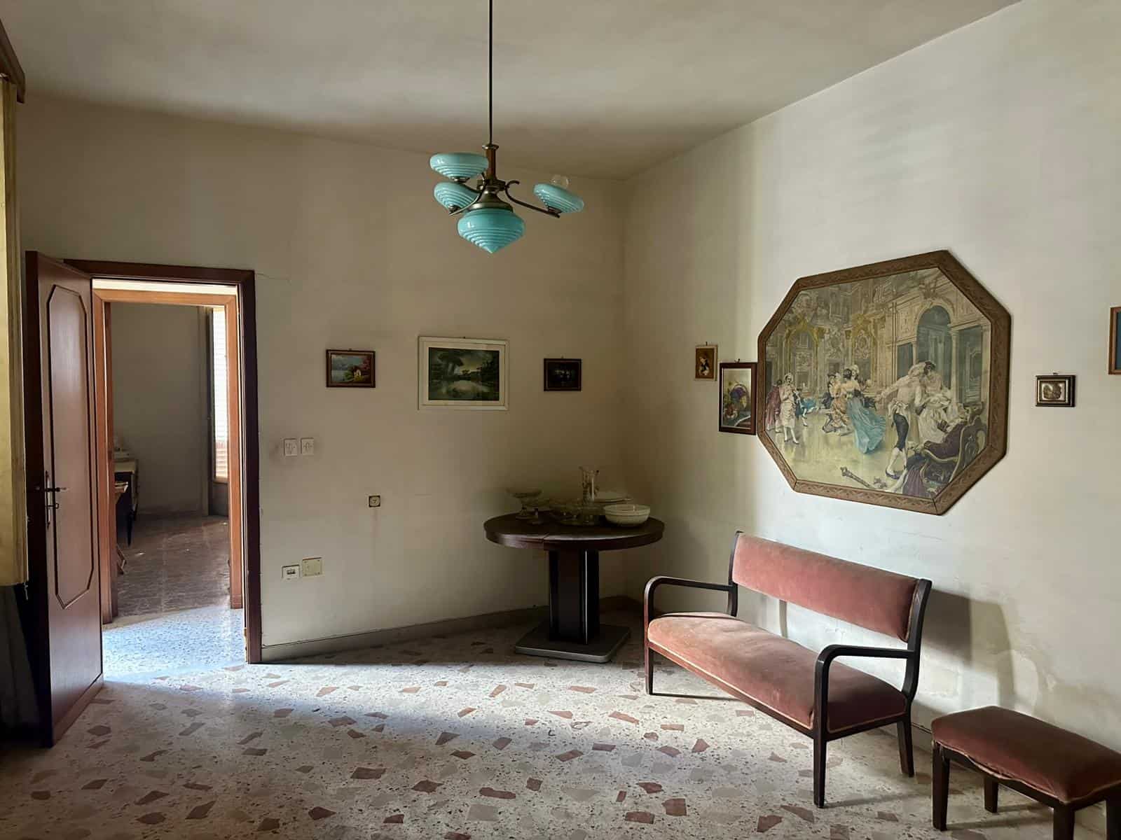 Soggiorno in stile vintage con pareti beige, lampadario azzurro, dipinti e un divano in velluto rosato, arredamento classico, cortile o stanza interna di una casa d'epoca.