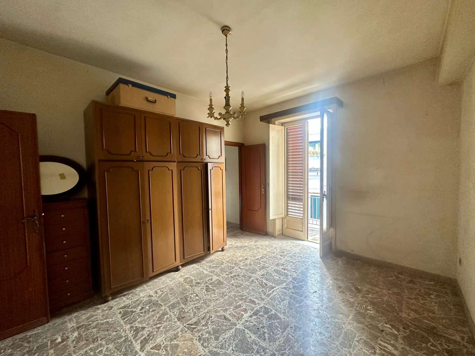 Armadio in legno antico in una stanza con porta finestra.