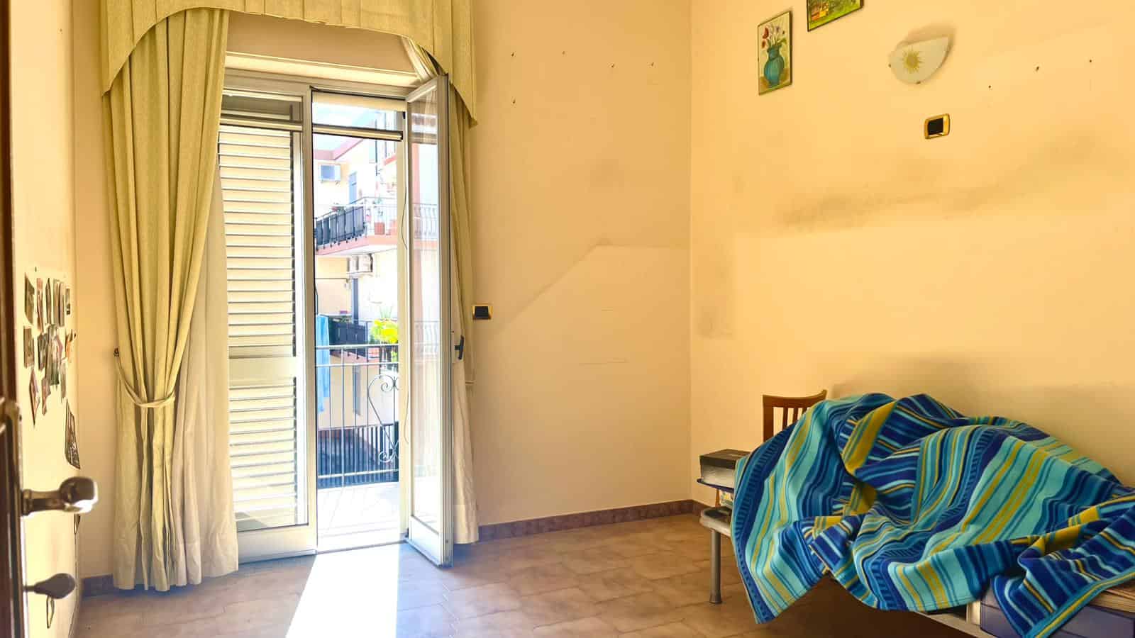 Balcone con vista sulla città, porta finestra con tende e patio, esempio di appartamento nextcasa.