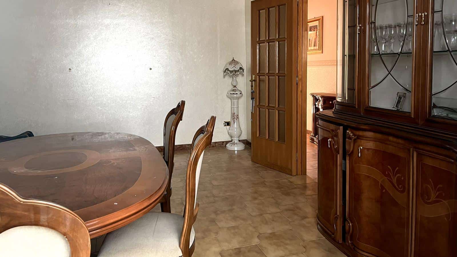 Antico vetrinetta in legno con stuzzico e cristalleria, sala da pranzo classica con tavolo e sedie in stile vintage, arredamento tradizionale in ambiente caldo e accogliente.