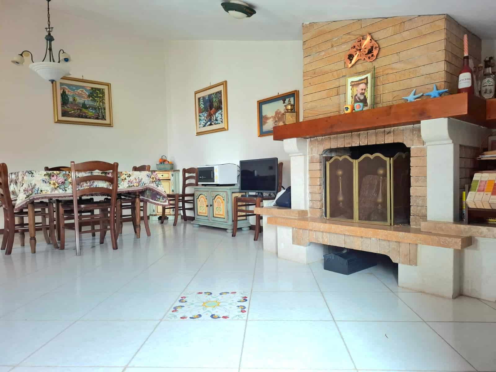 Camino in ceramica decorato con motivi floreali, soggiorno con camino in mattoni e mobili in stile classico, decorazioni artistiche alle pareti, ambienti accoglienti e ben arredati, ideale per famiglie e ricevimenti.