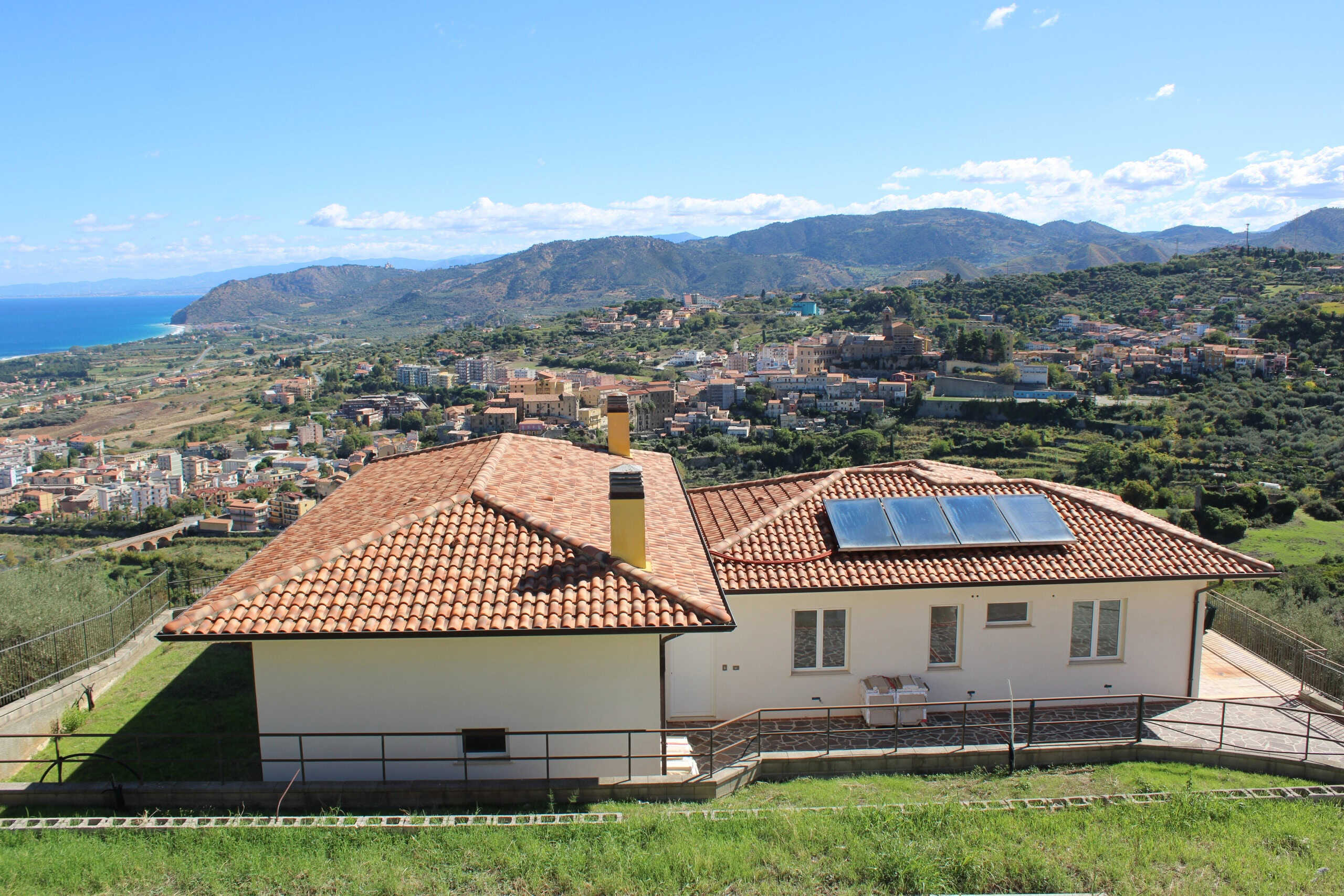 Villa con pannelli solari e vista panoramica sulla costa e le montagne, immersa nel verde, in vendita a NextCasa, agenzia immobiliare specializzata in case di alta qualità e sostenibili in Italia.