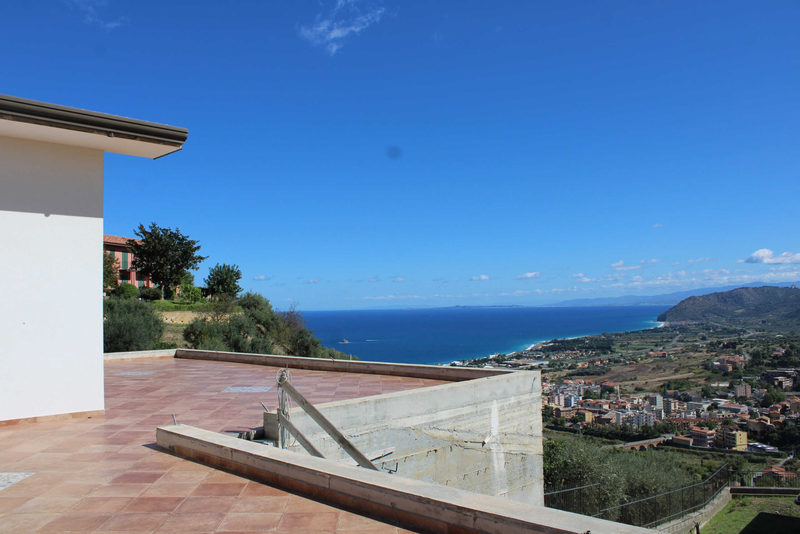 Vista panoramica del mare dalla terrazza di una casa moderna vicino al mare in Sicilia, con città e colline sullo sfondo, cielo blu e paesaggi mozzafiato, ideale per immobili e proprietà di lusso, angolo relax e co.