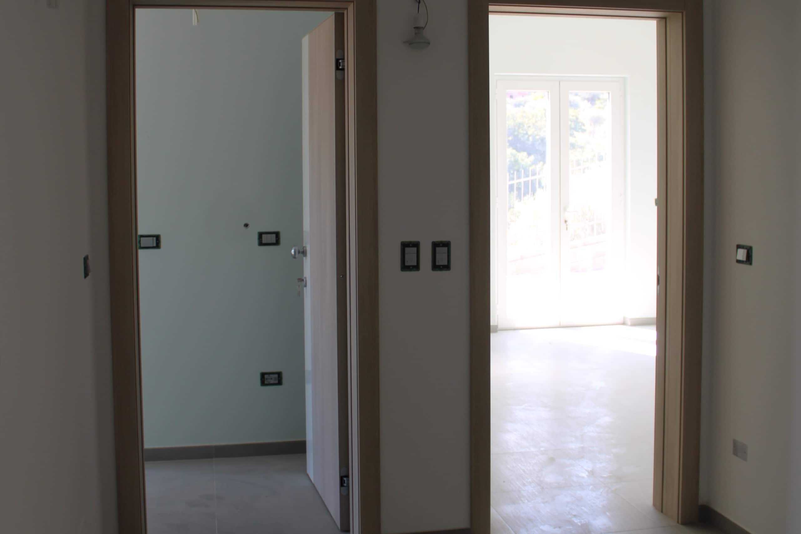 Elegante immobile in costruzione con ambienti luminosi e porte in legno naturale, ideale per investimenti immobiliari e proprietà di alta qualità.