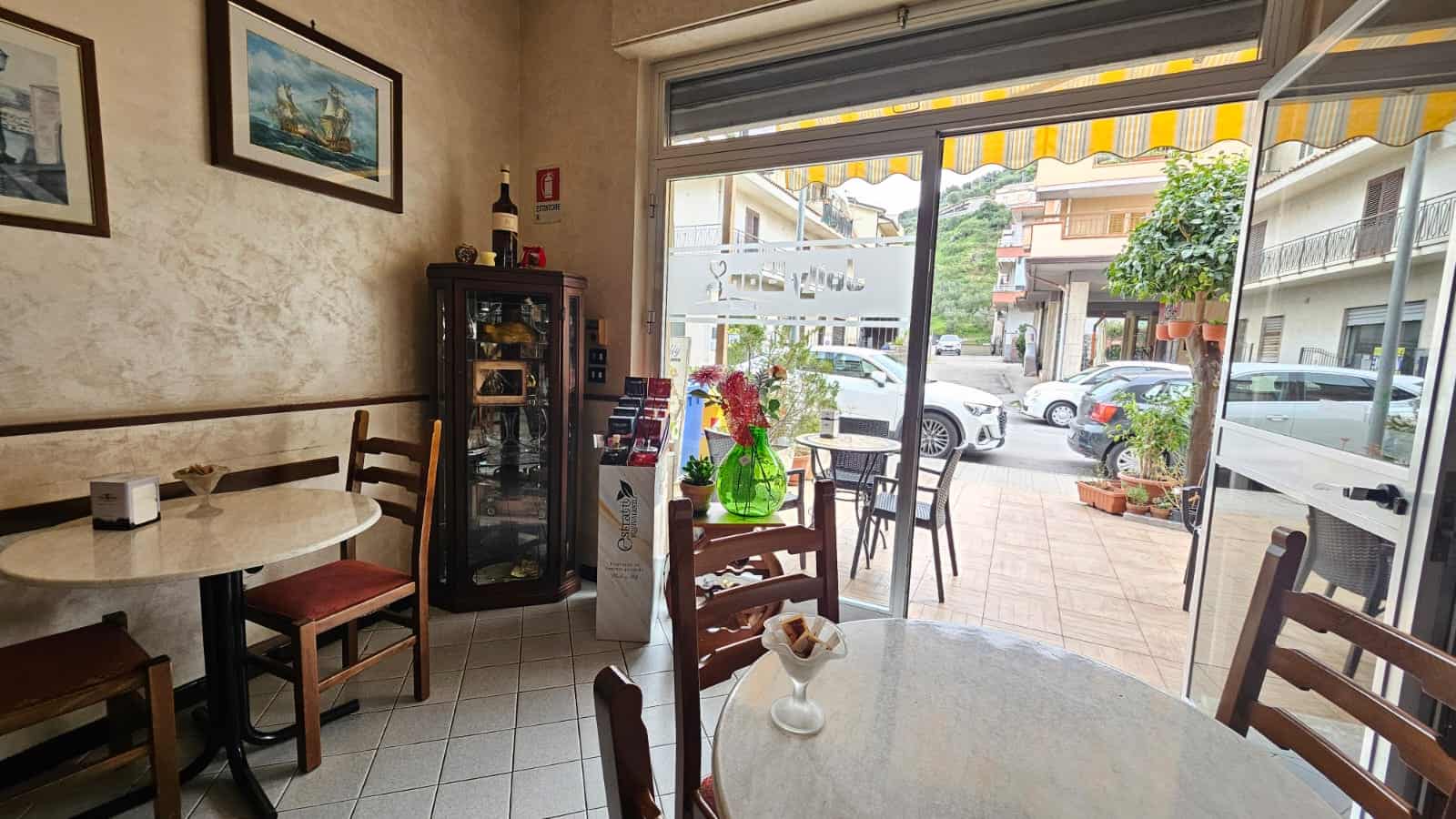 Mobili da ristorante01, arredamento tavolone e sedie, ambiente accogliente con vetrate panoramiche, stile casalingo rustico, atmosfera calda e luminosa, arredamento per locali pubblici, interior design NextCasa, stile vintage, decorazioni floreali.