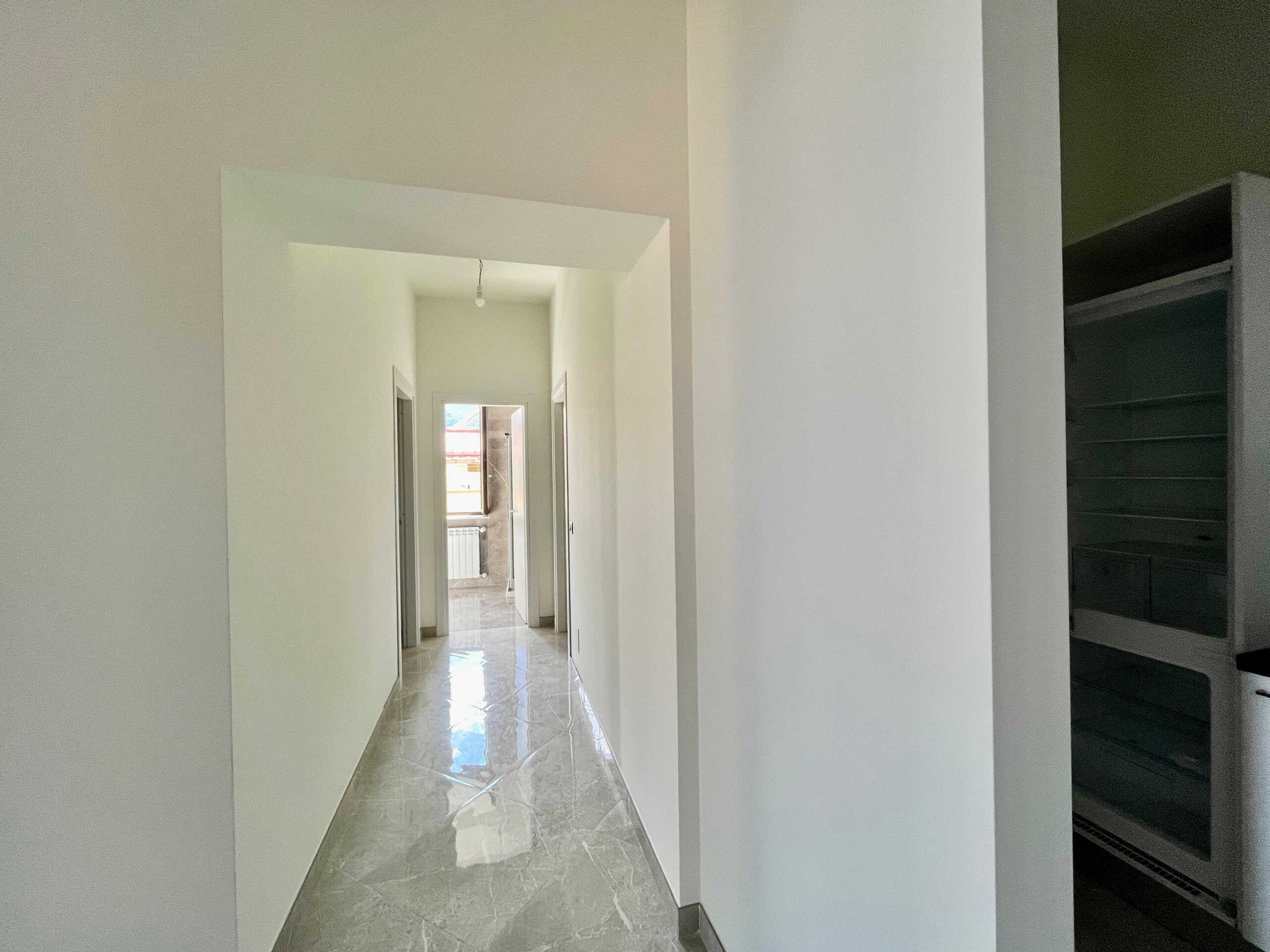 Prezzo di infilata di corridoio in una casa in costruzione o ristrutturata, pareti bianche, pavimento in gres effetto marmo, spazio luminoso e arioso, ideale per foto immobiliari, apparta in vendita o affitto.