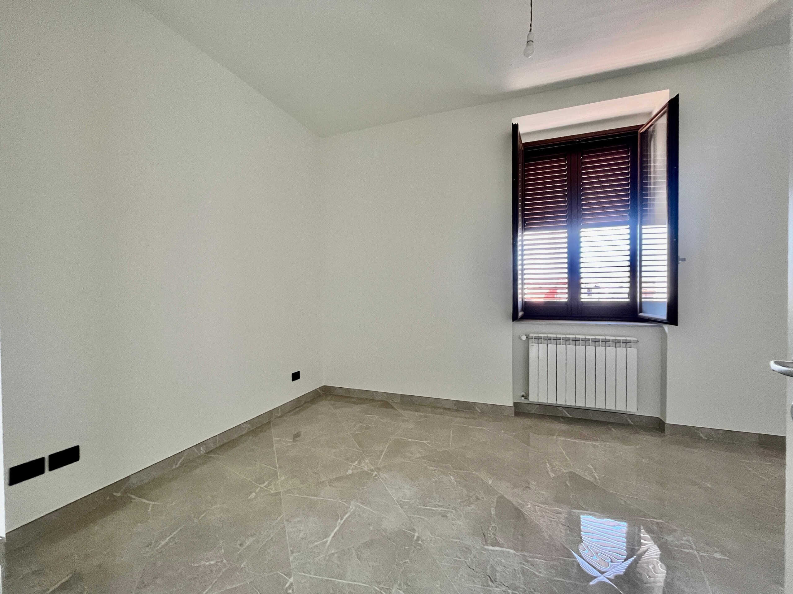 Lavagna, finestra con tapparelle in legno, stanza vuota con pareti bianche, pavimento in marmo lucido, riscaldamento a radiatori, aria naturale, immobile moderno, interni luminosi, ristrutturato, abitazione di nuova costruzione, decorazioni minimaliste, spazio abitativo di qualità, casa nuova, NextCasa, proprietà in vendita or affitto, immobili di prestigio.