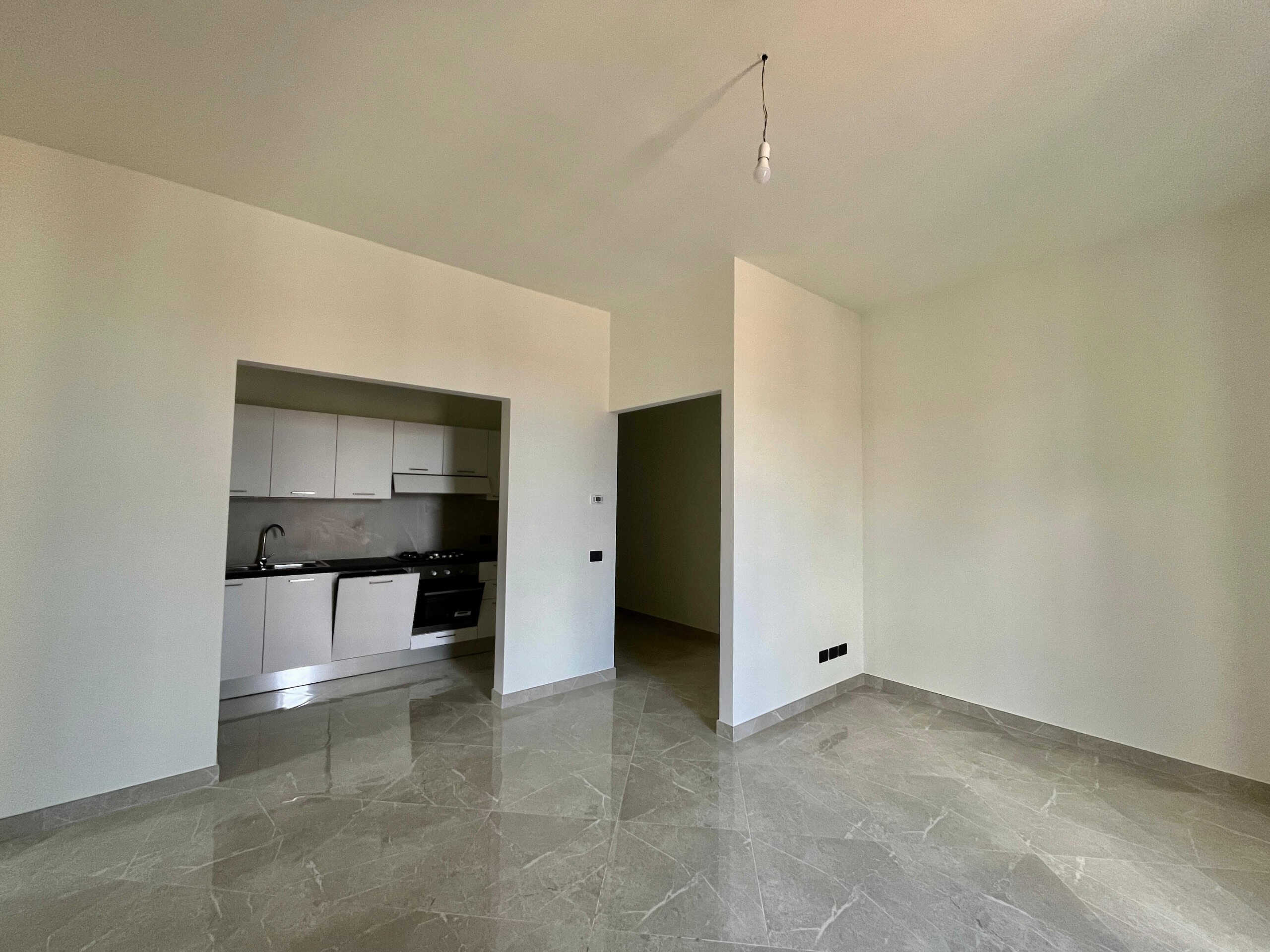 Nuova cucina moderna in appartamento pronto per essere arredato, con pareti bianche e pavimento in gres effetto marmo, ideale per soluzioni di arredamento personalizzate.