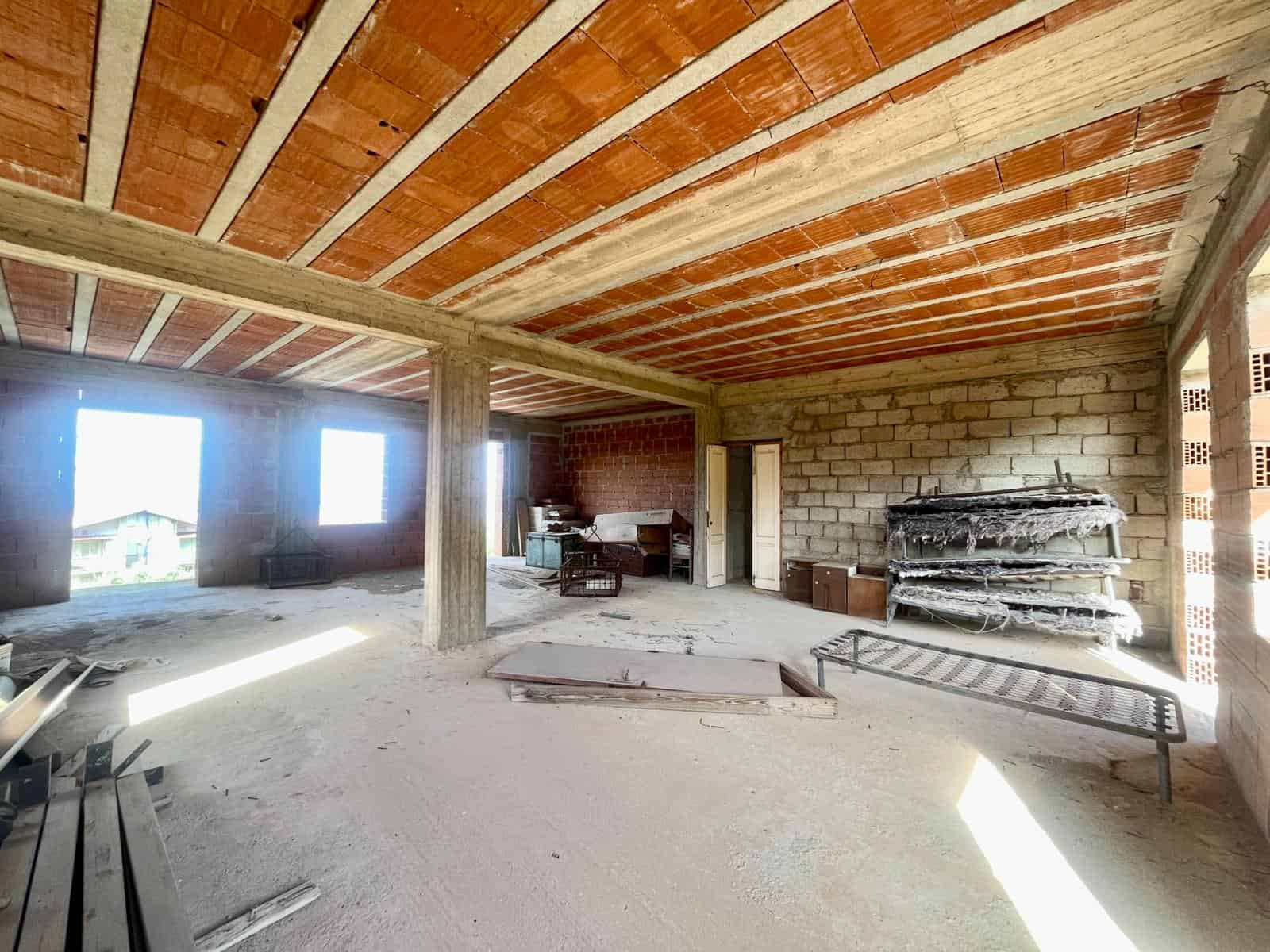 Cantiere di costruzione di una casa o appartamento, struttura in muratura e legno, ambiente interno con materiali edili e scaffali, pronta per essere rifinita e abitata.