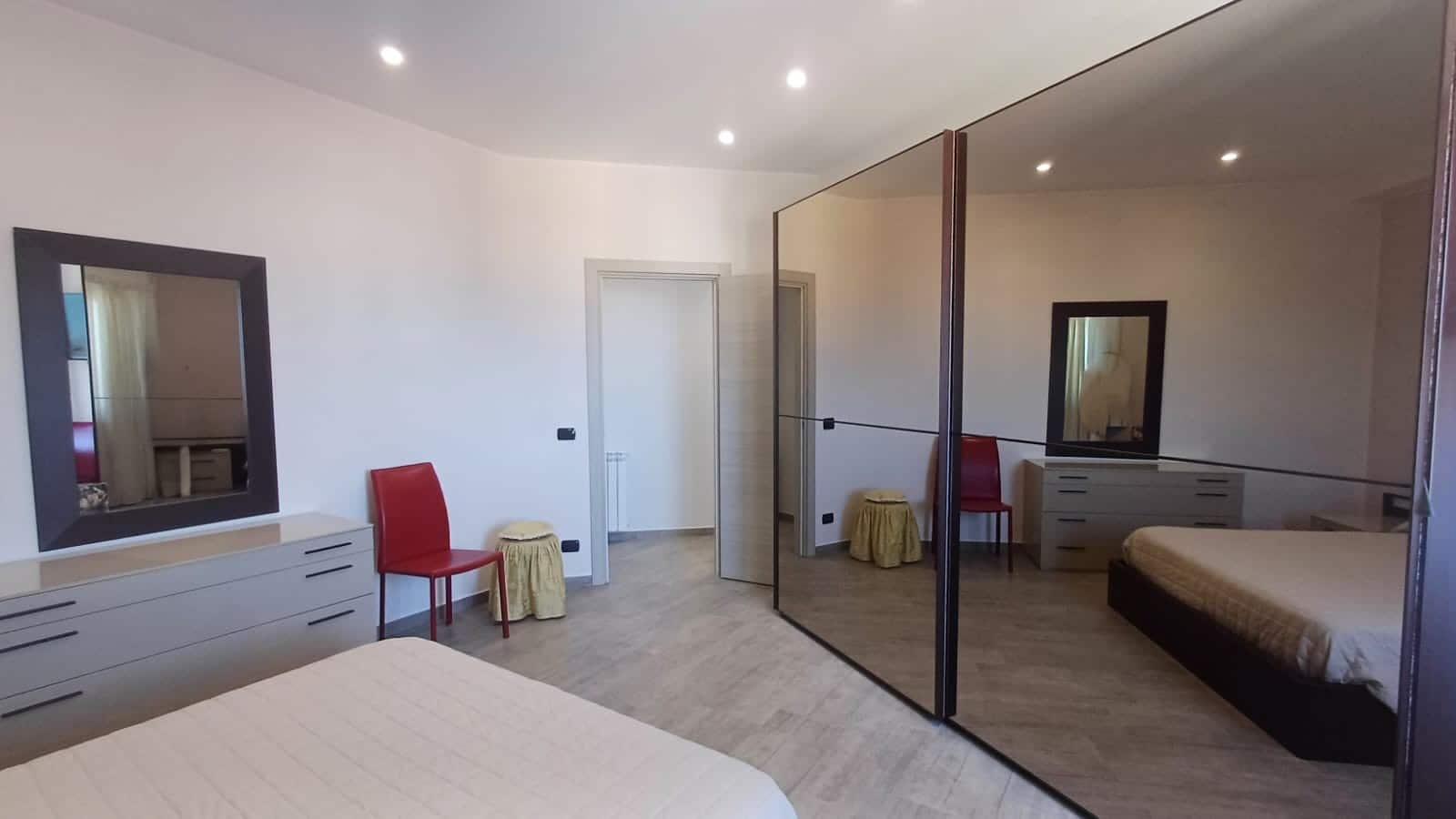 Porta armadio a specchio in camera da letto, arredamento moderno e funzionale, spazio luminoso e accogliente con mobili di design NextCasa per interni eleganti e pratici.