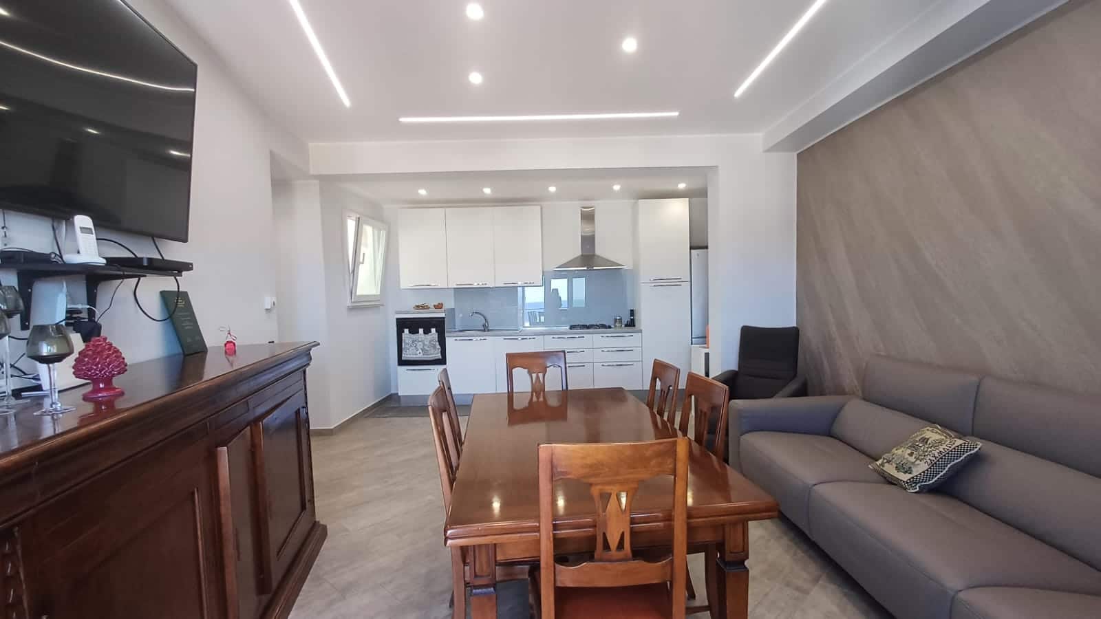 Moderno appartamento open space con cucina a vista, zona pranzo e area soggiorno con divano, interior design elegante e luminoso.