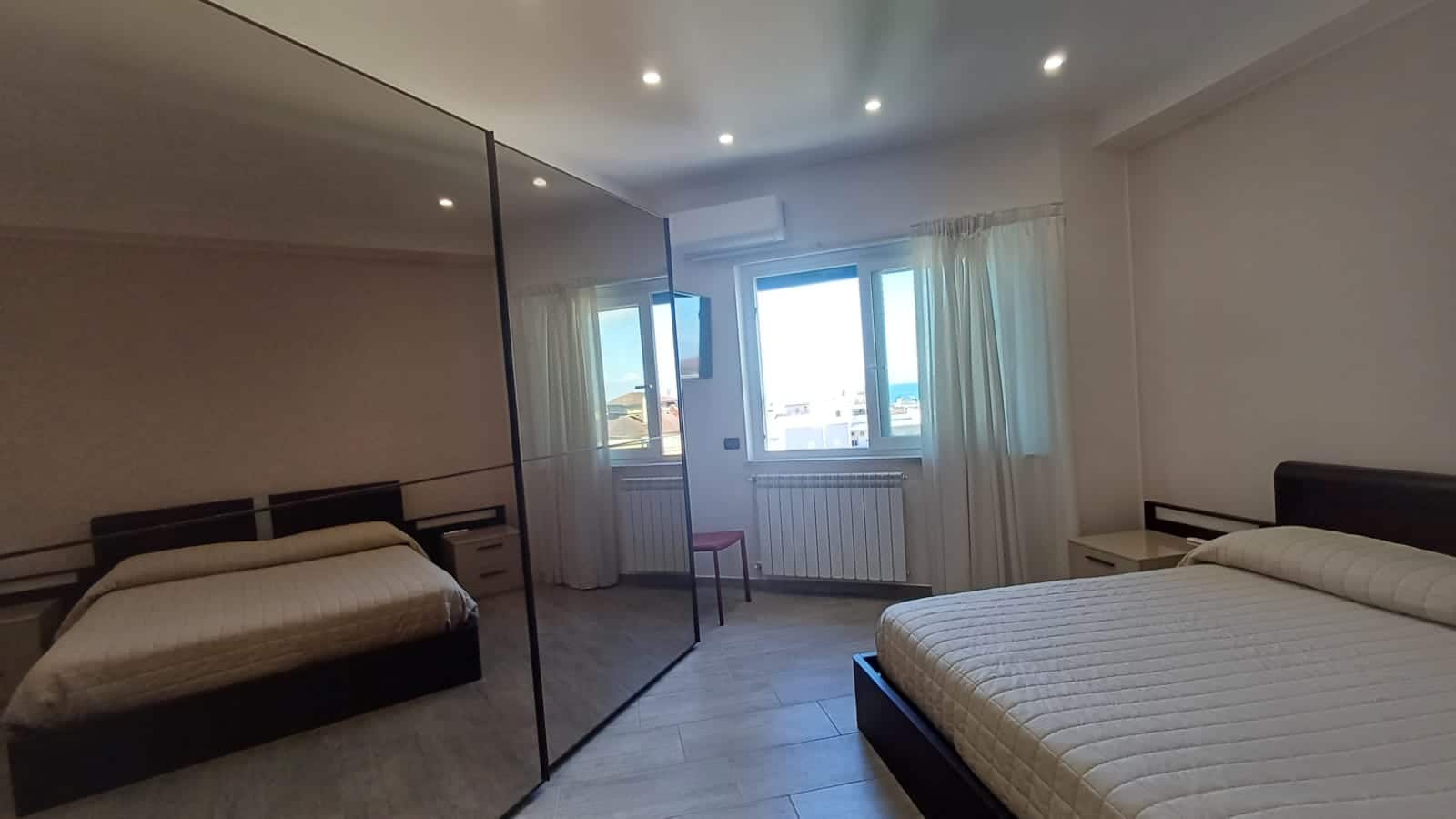 Moderno appartamento con camere da letto arredate, vista panoramica, finestre luminose e design elegante, ideale per acquisto o affitto, servizi inclusi, vicino al mare e ai principali servizi.