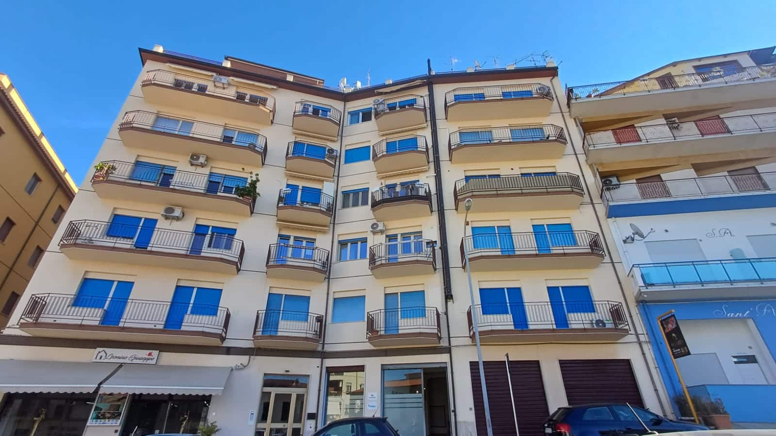 Balcone di appartamento residenziale in edificio moderno con serrande blu, balconi con ringhiera in metallo, clima, in un quartiere urbano di Napoli.