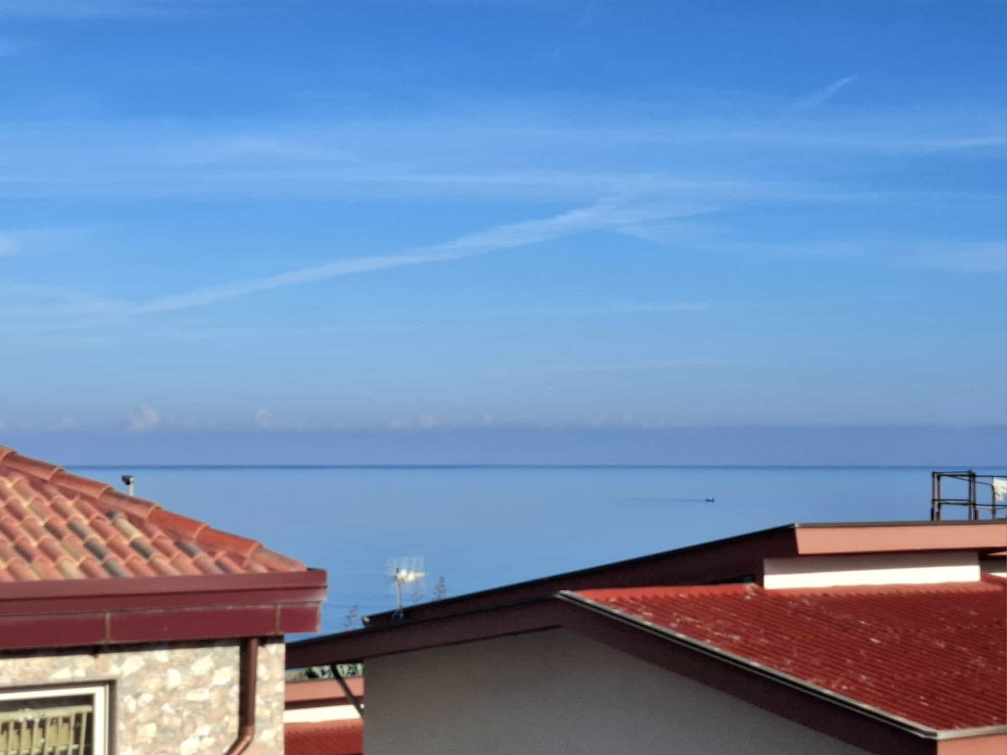 VISTA MARE - Tetto di case con tetti in terracotta rossa e immenso mare blu in lontananza, cielo sereno, paesaggio costiero, atmosfera rilassante, panorama panoramico, esclusiva vista mare.