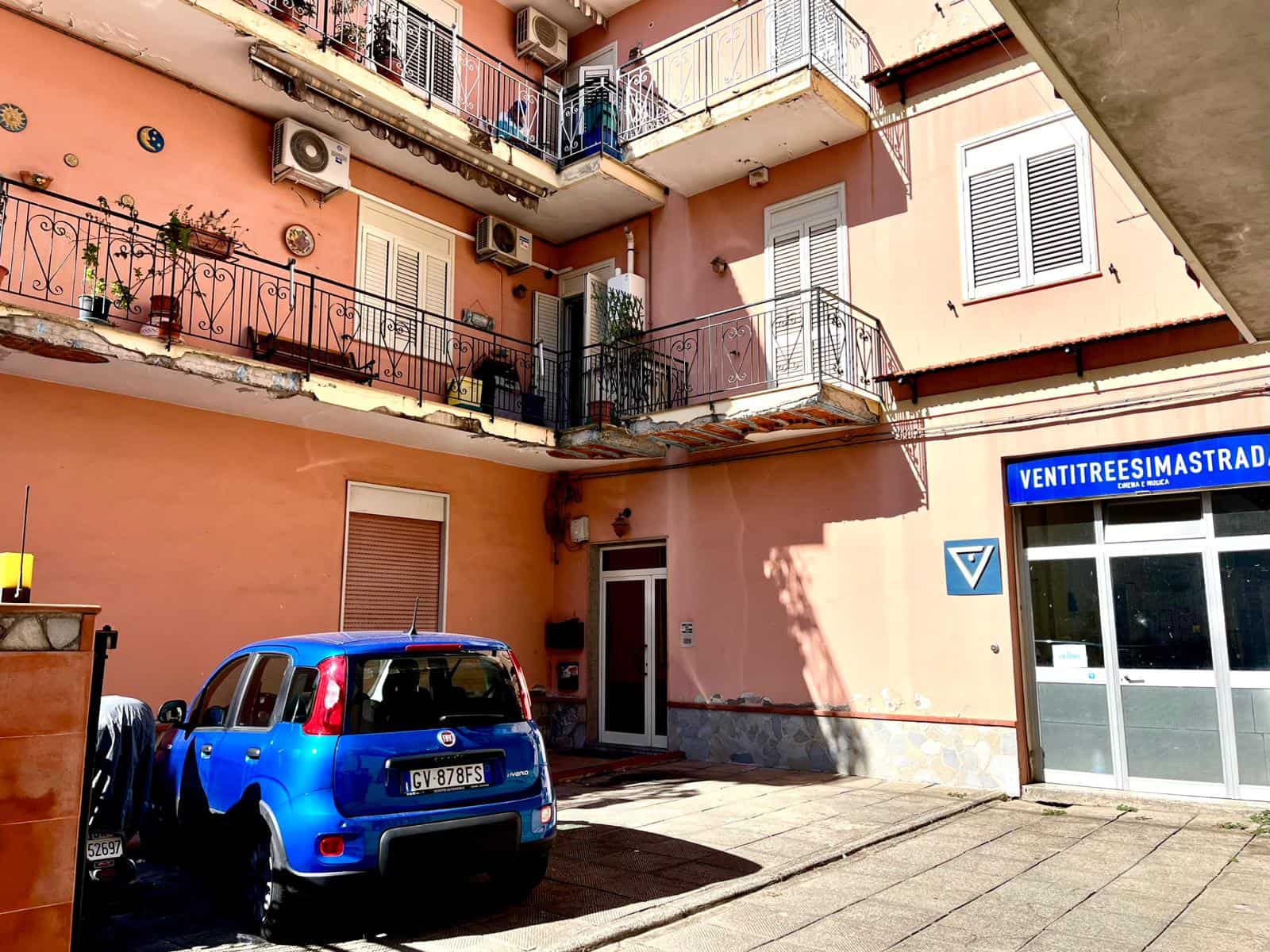 Fiore all'occhiello di NextCasa, questo appartamento in affitto si trova in un tranquillo complesso residenziale di Napoli. La facciata esterna è di un caldo color pesca con balconi decorati con piante e luci, mentre un'auto blu parcheggiata davanti evidenzia la posizione strategica nella città. L'immobile è dotato di aria condizionata, finestre con persiane e ampi spazi esterni, ideali per vivere in un contesto urbano con comfort e praticità. Un'ottima soluzione per chi cerca una casa in una zona centrale e ben servita di Napoli.