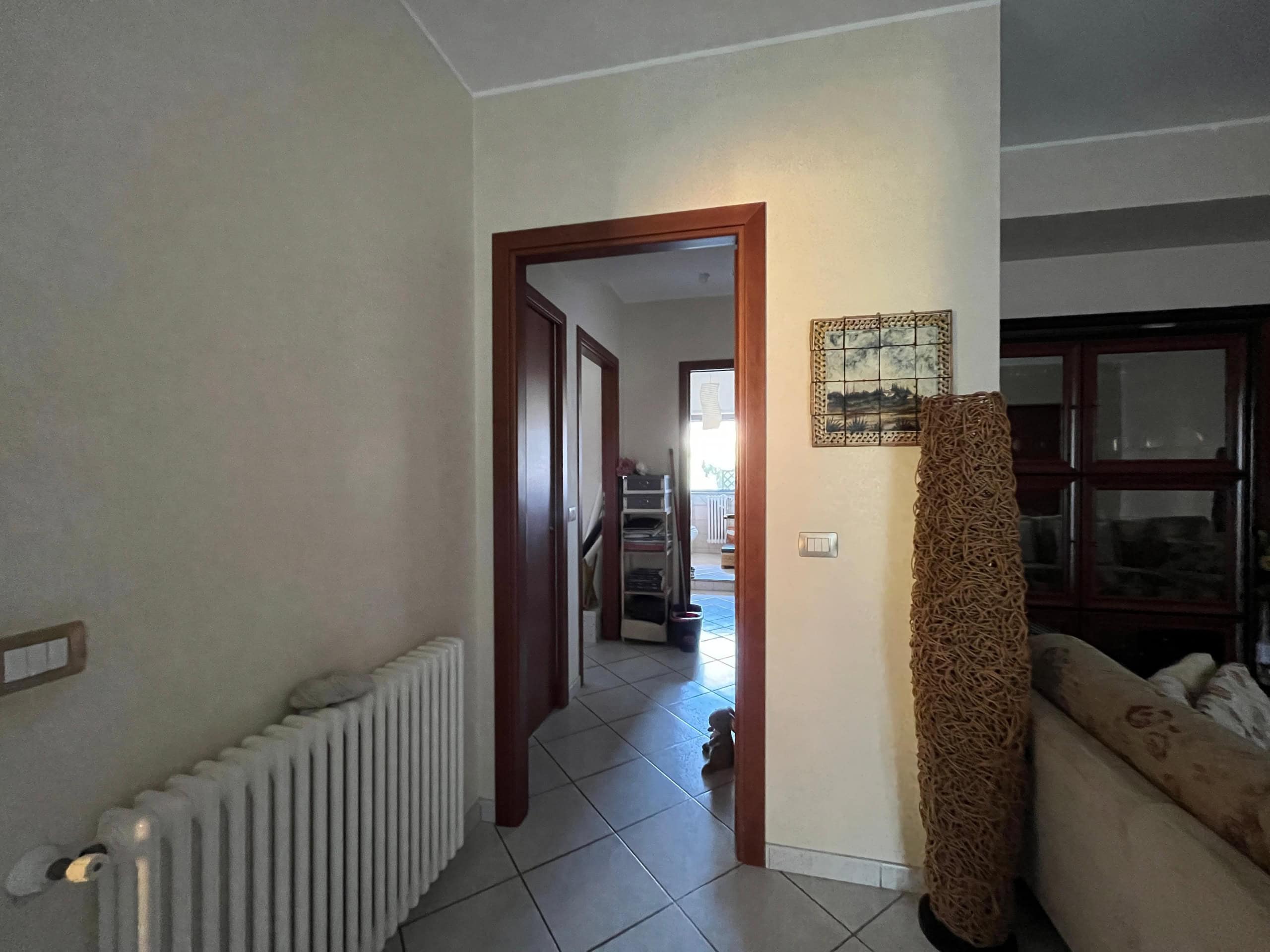 Radiatore in soggiorno, ingresso alla zona giorno con dettagli di arredo e pareti colorate, spazi abitativi funzionali e ben organizzati.