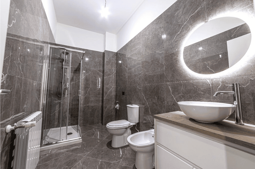 Lavabo moderno con specchio luminoso e bagno con doccia in un elegante interno di casa NextCasa. Ambiente ristrutturato con finiture di alta qualità e design contemporaneo.