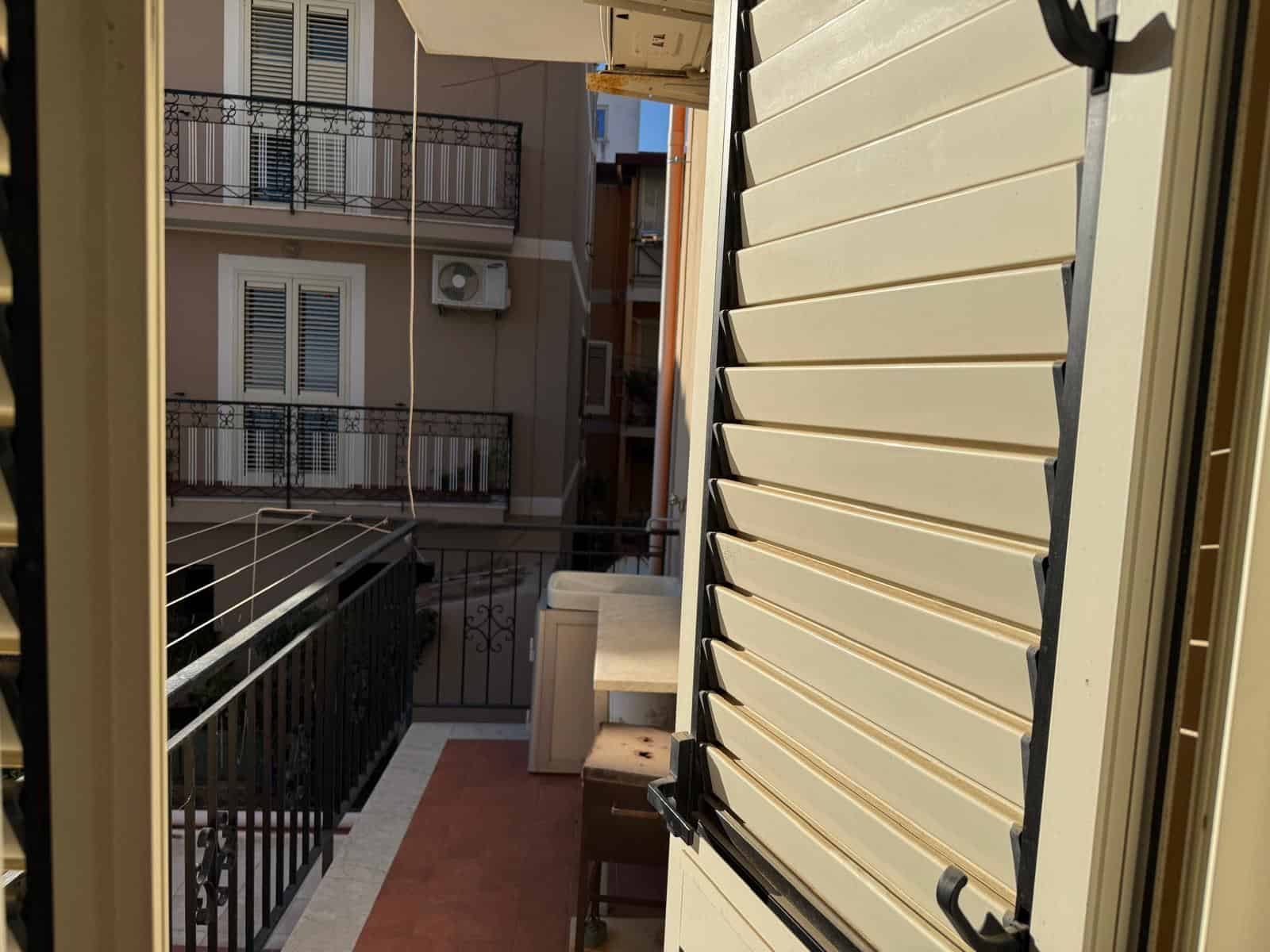 Persiana orientabile su balcone di appartamento con vista su altre unità immobiliari, in città. Prospettiva esterna dell'edificio residenziale con arredi e dettagli architettonici.