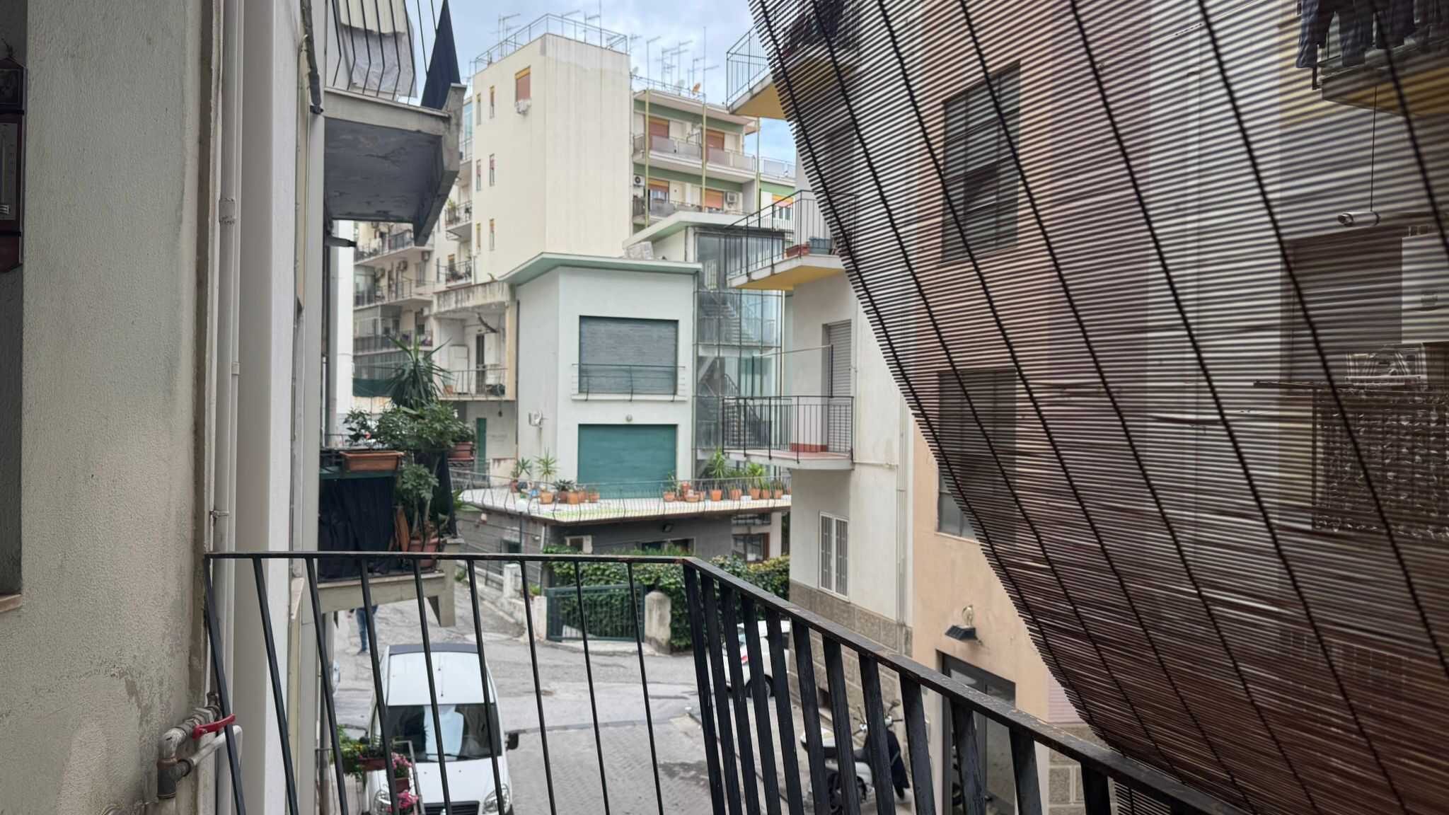 Balcone con tettoia in bambù e vista su edifici residenziali in quartiere urbano, perfetto per appartamenti moderni e ristrutturati, con spazi esterni pratici e accoglienti.