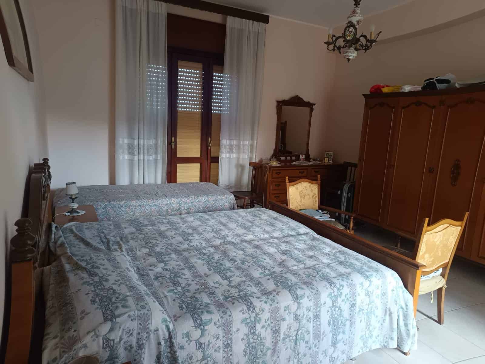 1. Camera da letto matrimoniale in stile classico con mobili in legno, doppio letto, armadio e specchio, ambiente luminoso e accogliente.