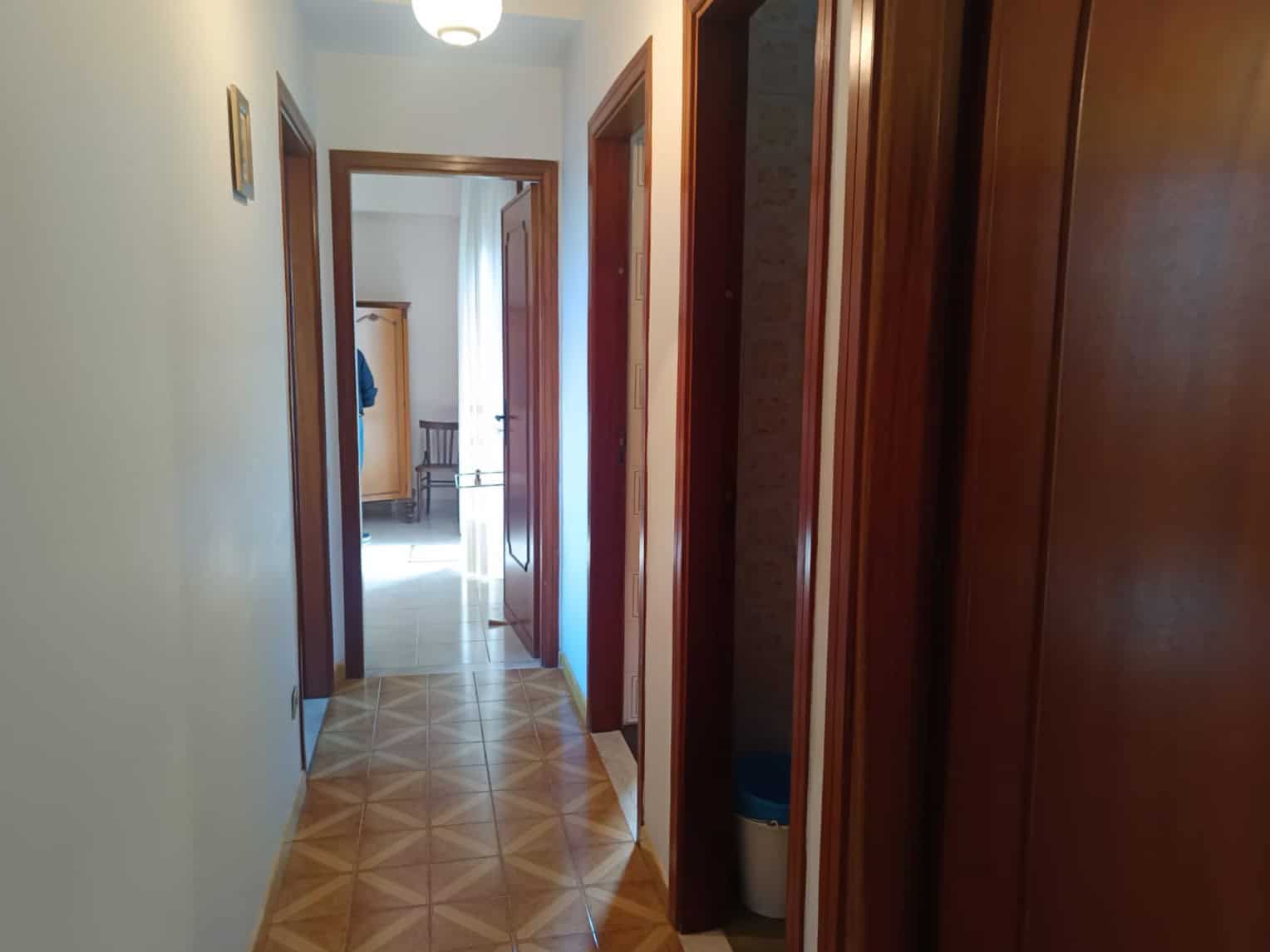 Ampio corridoio interno di casa NextCasa con mobili, ampie porte in legno e pavimentazione in parquet, luminoso e accogliente, ideale per vivere in comfort e stile.