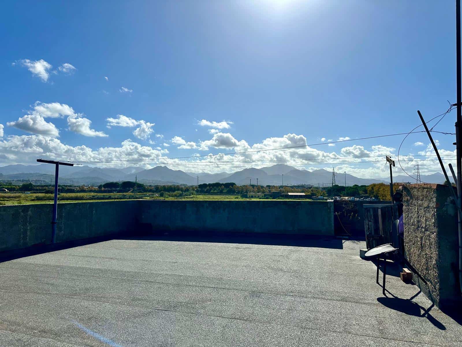 Vista panoramica di un terrazzo con cielo sereno, nuvole e montagne sullo sfondo, ideale per soggiorni all'aperto e relax all'aria aperta in ambienti residenziali.