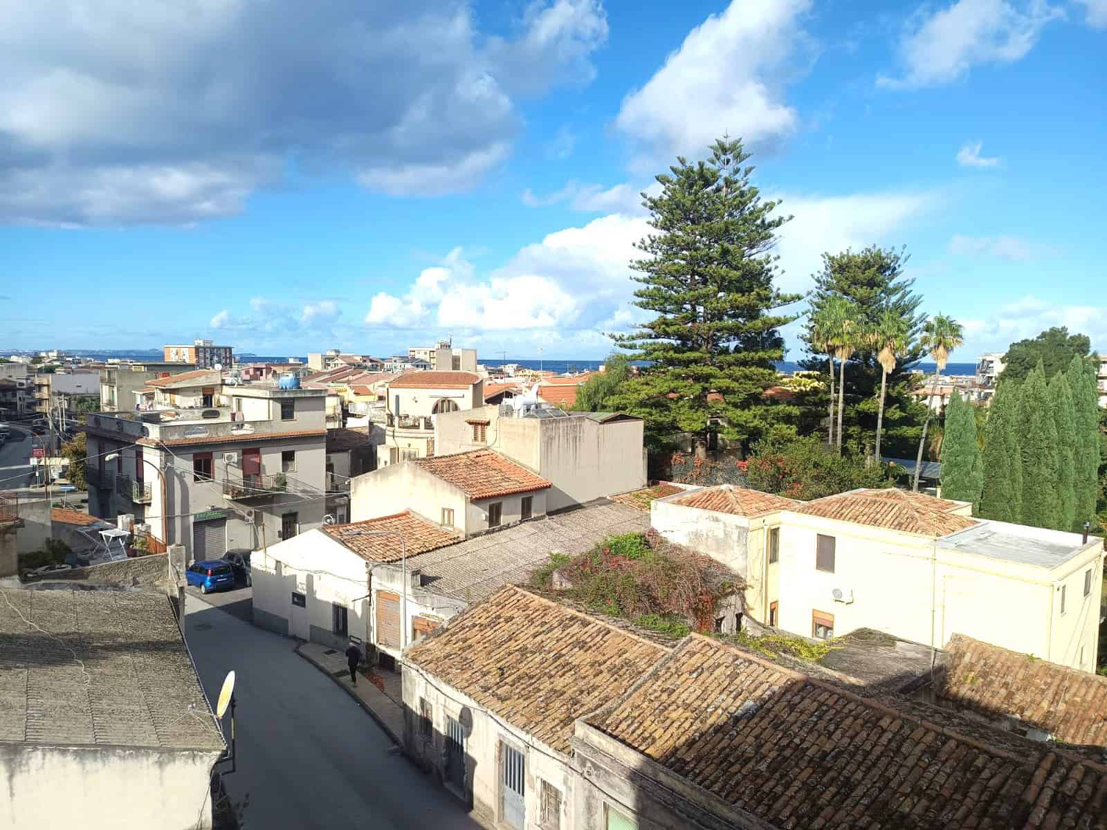 VISTA PANORAMICA DELLE CASE DI MARE E ARBUSTI DI FRONTE AL MARE A RAGUSA Ibla, SICILIA, ITALIA. LA VISTA INCLUDE ALBERI, TETTI IN TILT E IL MARE NUOVO IN SFONDO.
