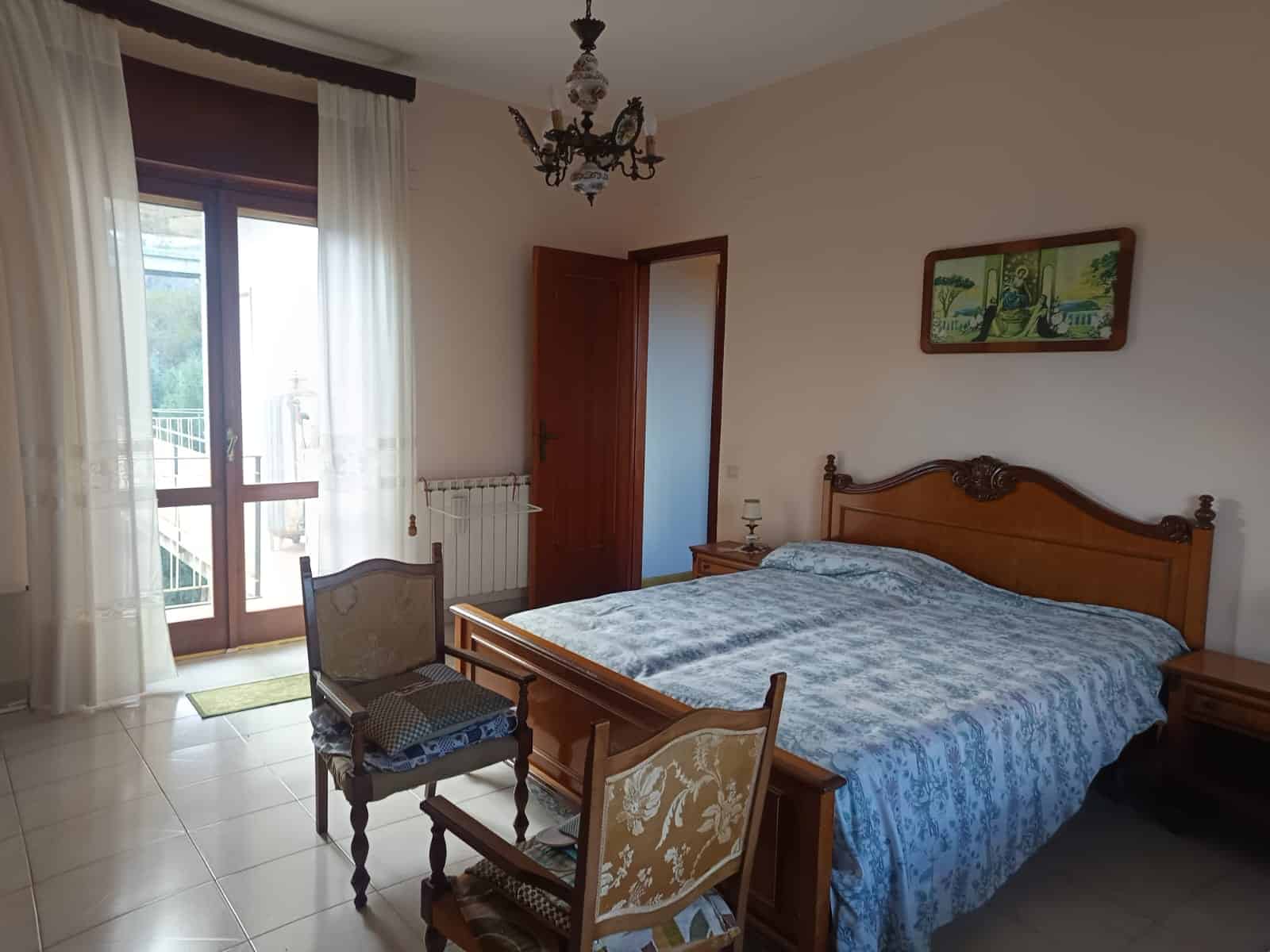 Appartamento con camera da letto elegante e luminosa, arredamento classico in legno, balcone con vista, ambiente accogliente e spazioso, ideale per soggiorni di comfort e relax a NextCasa.