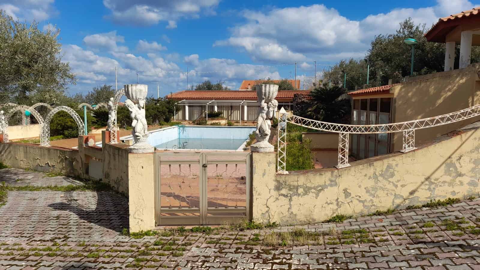 Piscina all'aperto con statua decorativa e Recinzione in ferro battuto in un giardino privato di proprietà NextCasa.