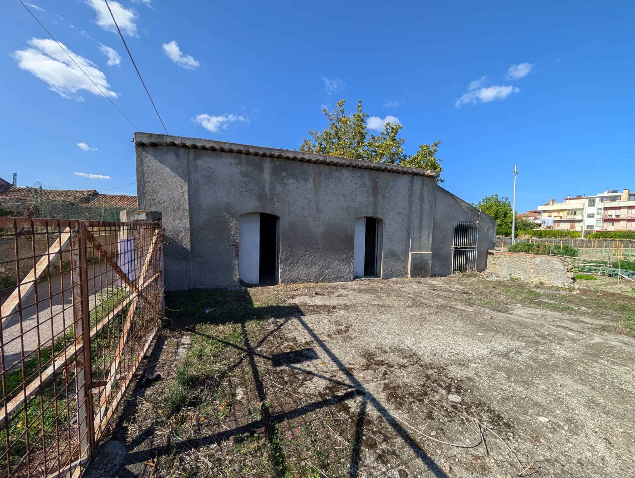 Vecchio edificio in pietra da ristrutturare, situato in un'area tranquilla con spazi aperti e cielo sereno, ideale per progetti di ristrutturazione o investimento immobiliare nel contesto residenziale.