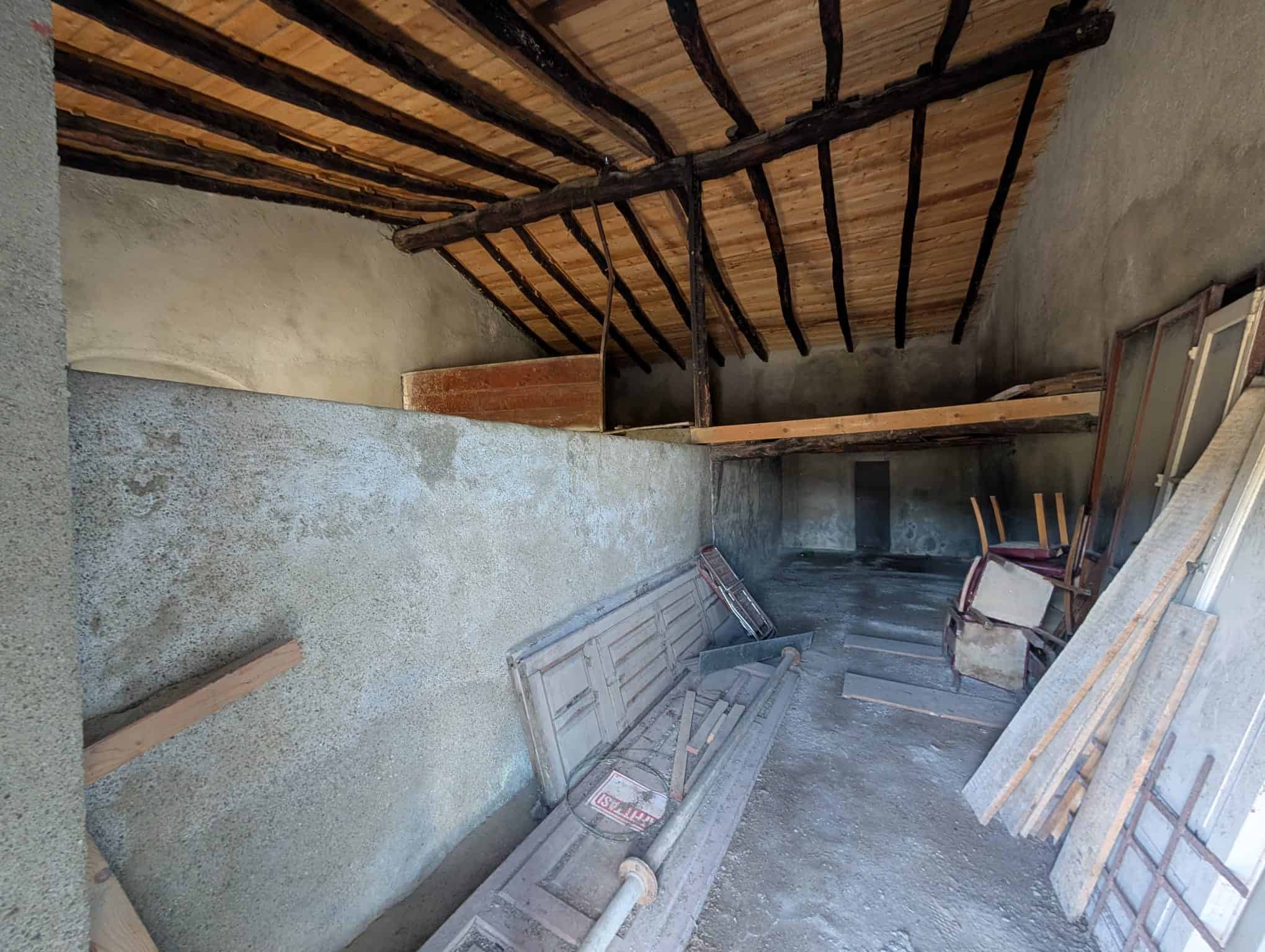 Prezzo immobile in costruzione, soffitto con travi di legno, pareti in calce grezza, spazio interno in fase di ristrutturazione, elementi di edilizia tradizionale, ambiente per progetto di ristrutturazione casa, foto di un sottotetto rustico non finito, immobile da personalizzare, spazio abitativo in fase di sviluppo, elementi architettonici in legno e calcestruzzo, lavori di costruzione e ristrutturazione.