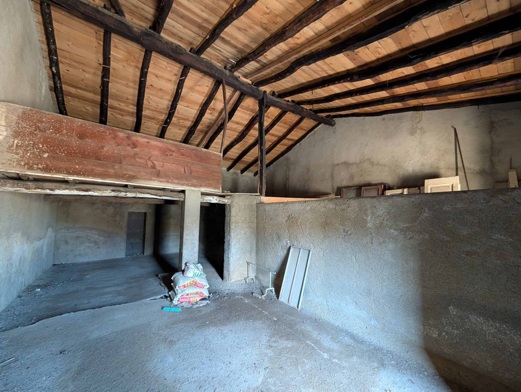 Finestra sul tetto di un'unità abitativa in costruzione o ristrutturazione, con struttura in legno e pareti in cemento, pronto per essere rifinito, rappresentando l'interior design rustico o industriale.