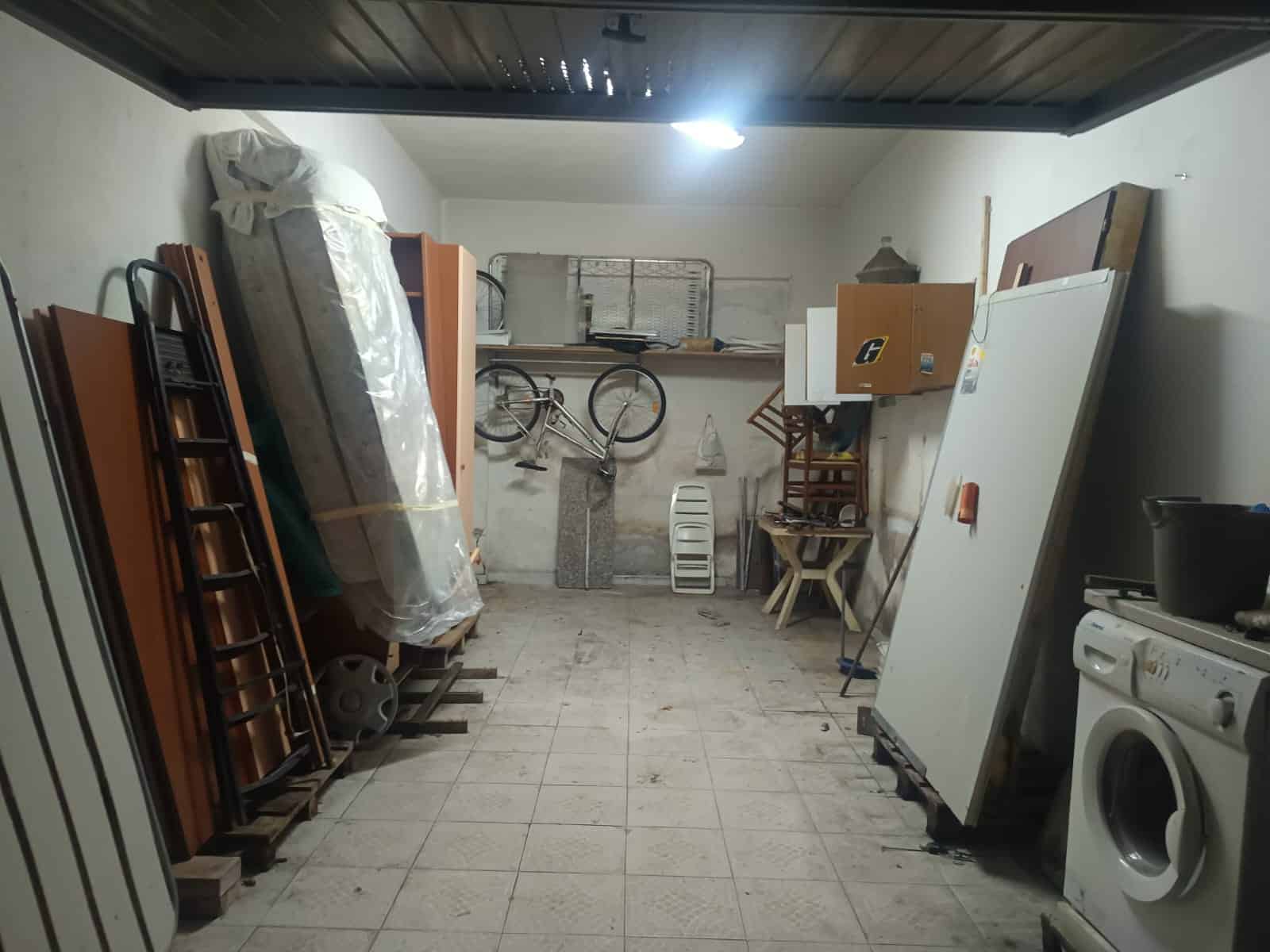 Ripostiglio garage con attrezzature e mobili, scaffali, biciclette e lavatrice, spazio organizzato per il deposito di oggetti vari, ideale per ottimizzare gli ambienti di casa.