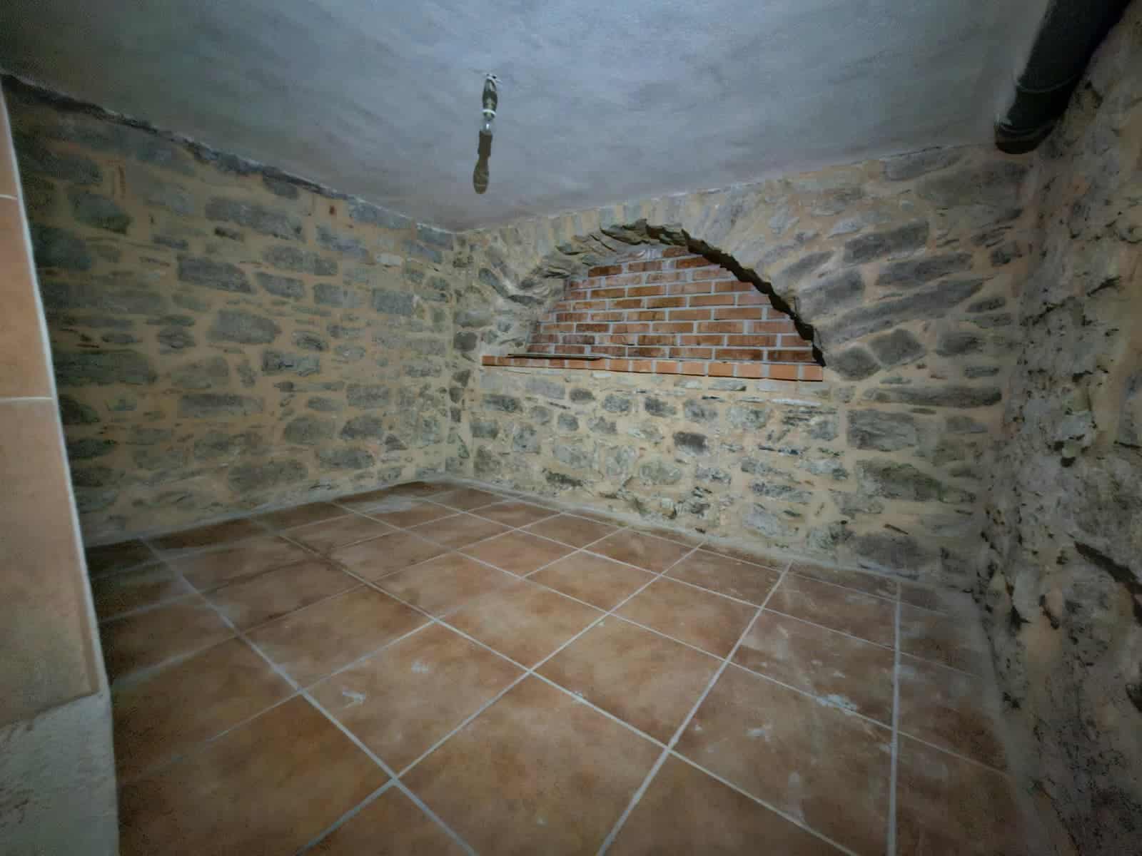 Locale in pietra e mattoni con soffitto inclinato e rivestimenti in muratura, spaziosa e luminosa, ideale per taverne o ambienti rustici, con pavimento in piastrelle terracotta.