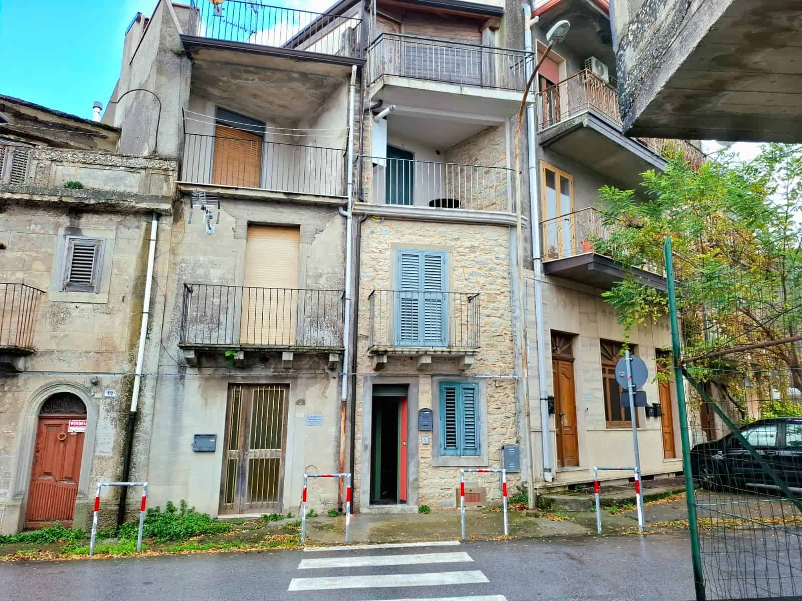Ubicazione di un edificio residenziale storico in una strada tranquilla, con facciata in pietra, balconi in ferro battuto, finestre con tapparelle e ingresso in legno, in un quartiere attivo e vivace.