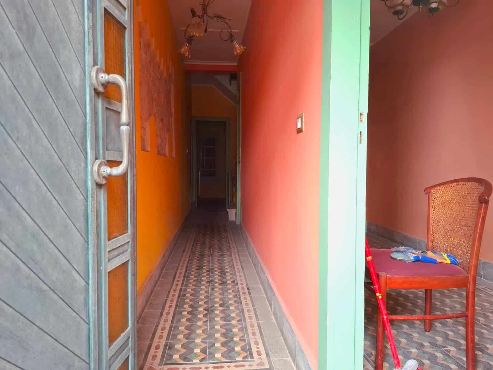 Chevron, Corridoio interno di una casa con pareti colorate e pavimento in piastrelle decorative, vista dall'ingresso che mostra un ambiente colorato e accogliente.