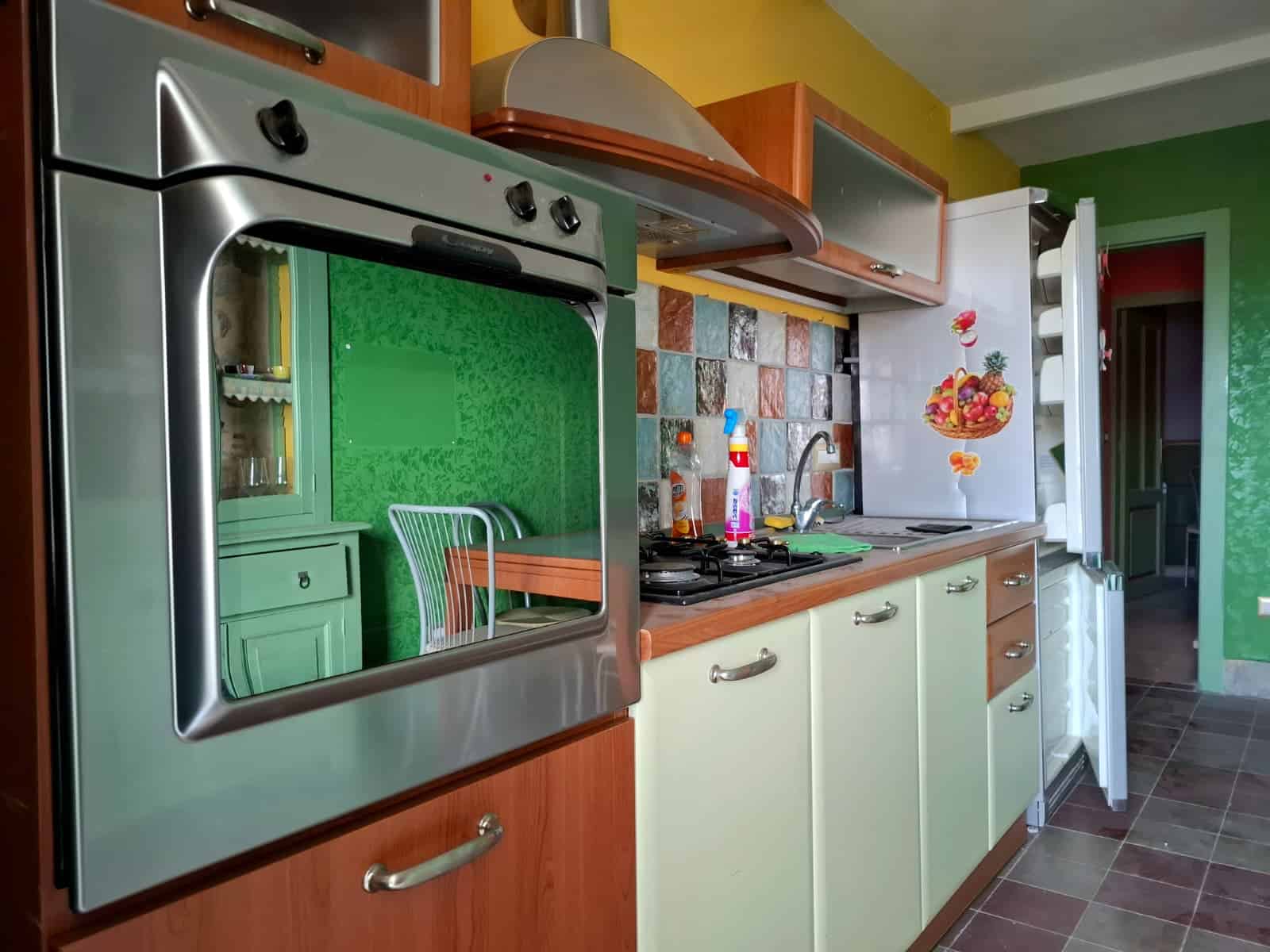 Forno a microonde con riflettore in cucina, arredamento colorato, piano di lavoro in mattonelle di vari colori, ambiente accogliente e funzionale, ideale per l'acquisto di immobili con la consulenza di NextCasa.