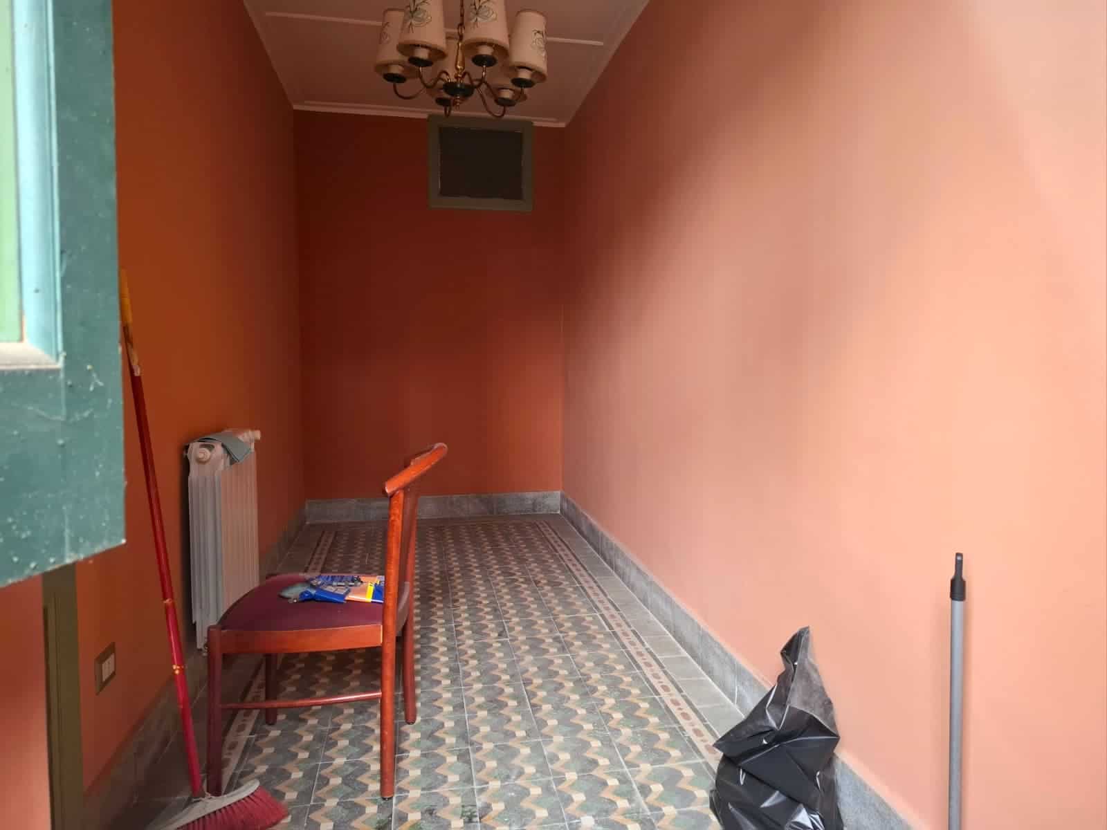 FOTO DI UNA VERANDA INTERNA CON PARETI ARANCIONI, PAVIMENTO IN CERAMICA COLORATA, POLTRONA IN LEGNO, SCHEDE E ACCESSORI PER LA CASA.