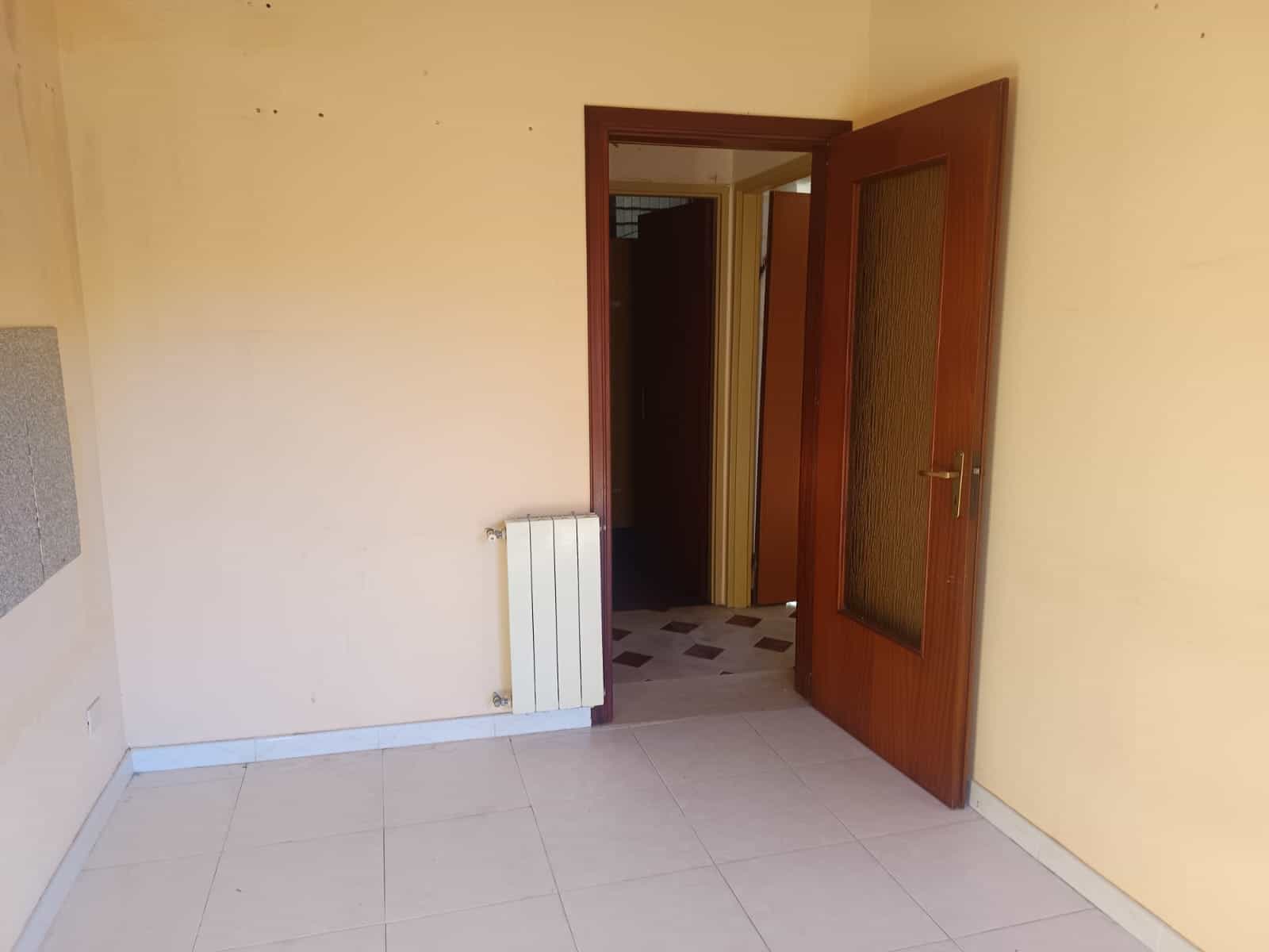 Porta interna in legno con vetrino, vista da una stanza con pareti color beige e pavimento in piastrelle chiara, spazio abitativo luminoso e funzionale.