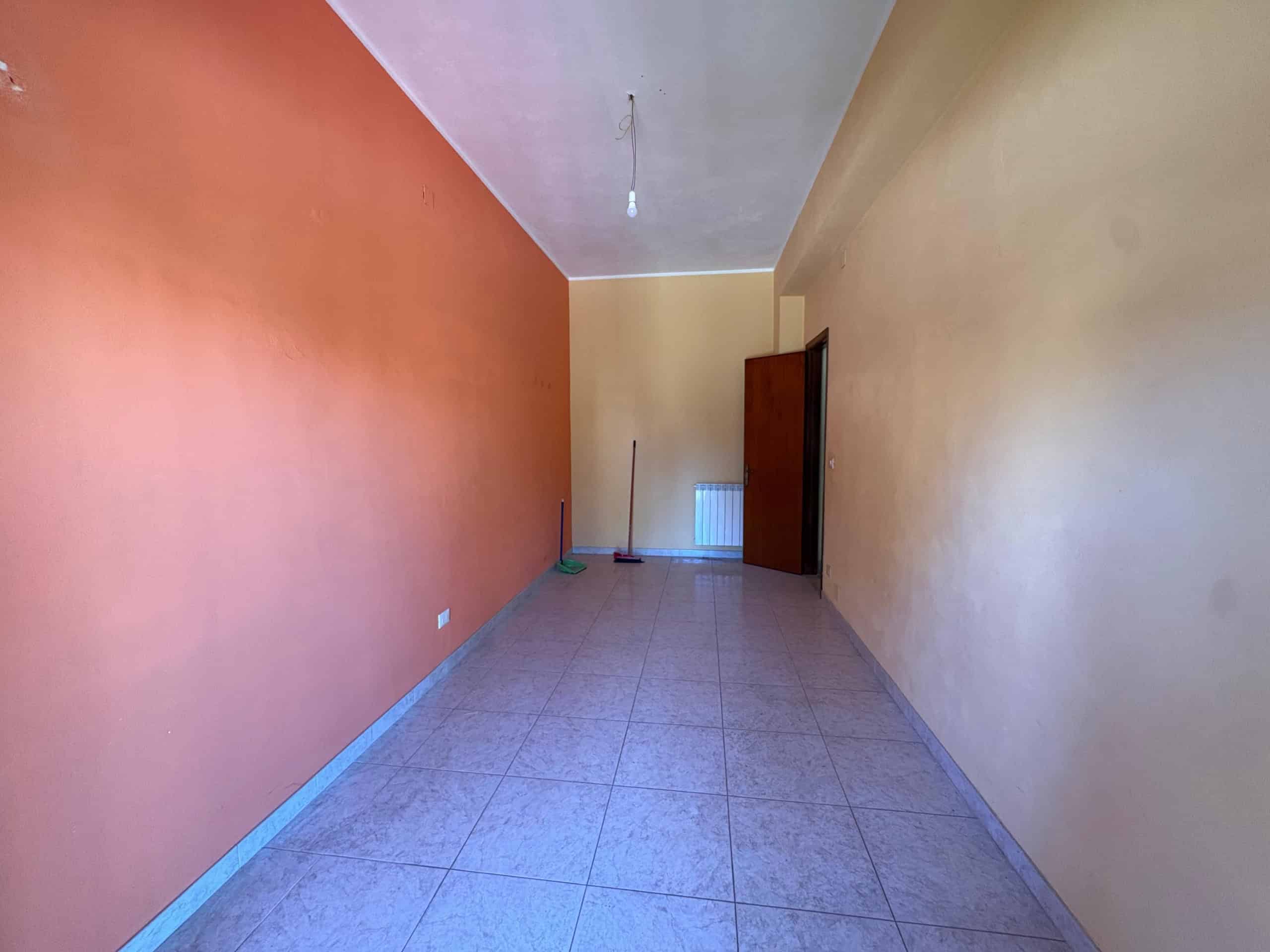 Ampio soggiorno in fase di ristrutturazione con pareti colorate, pavimento in gres, ingresso con porta in legno, spazi luminosi e pratici, ideale per personalizzare la propria casa.