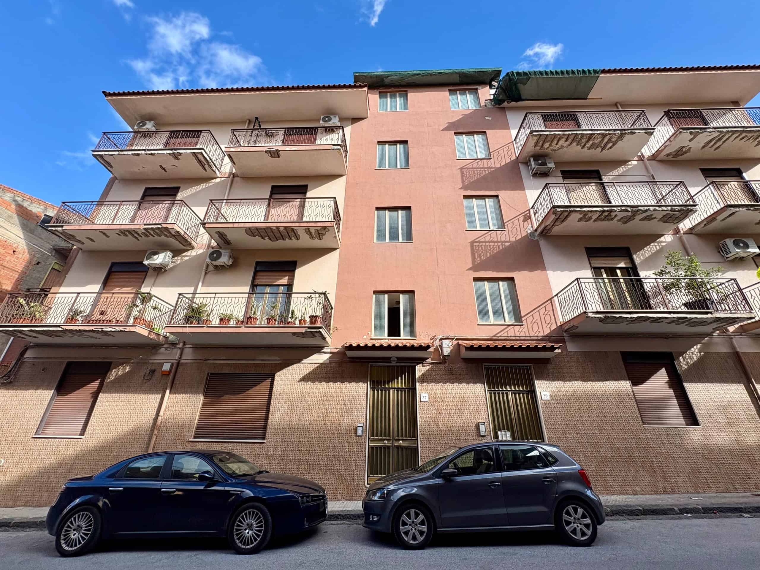 Ampio edificio residenziale con balconi in ferro battuto, facciata rosa e interni moderni, situato in zona centrale. Ideale per investimento immobiliare e affitti di lunga durata, con parcheggio privato.