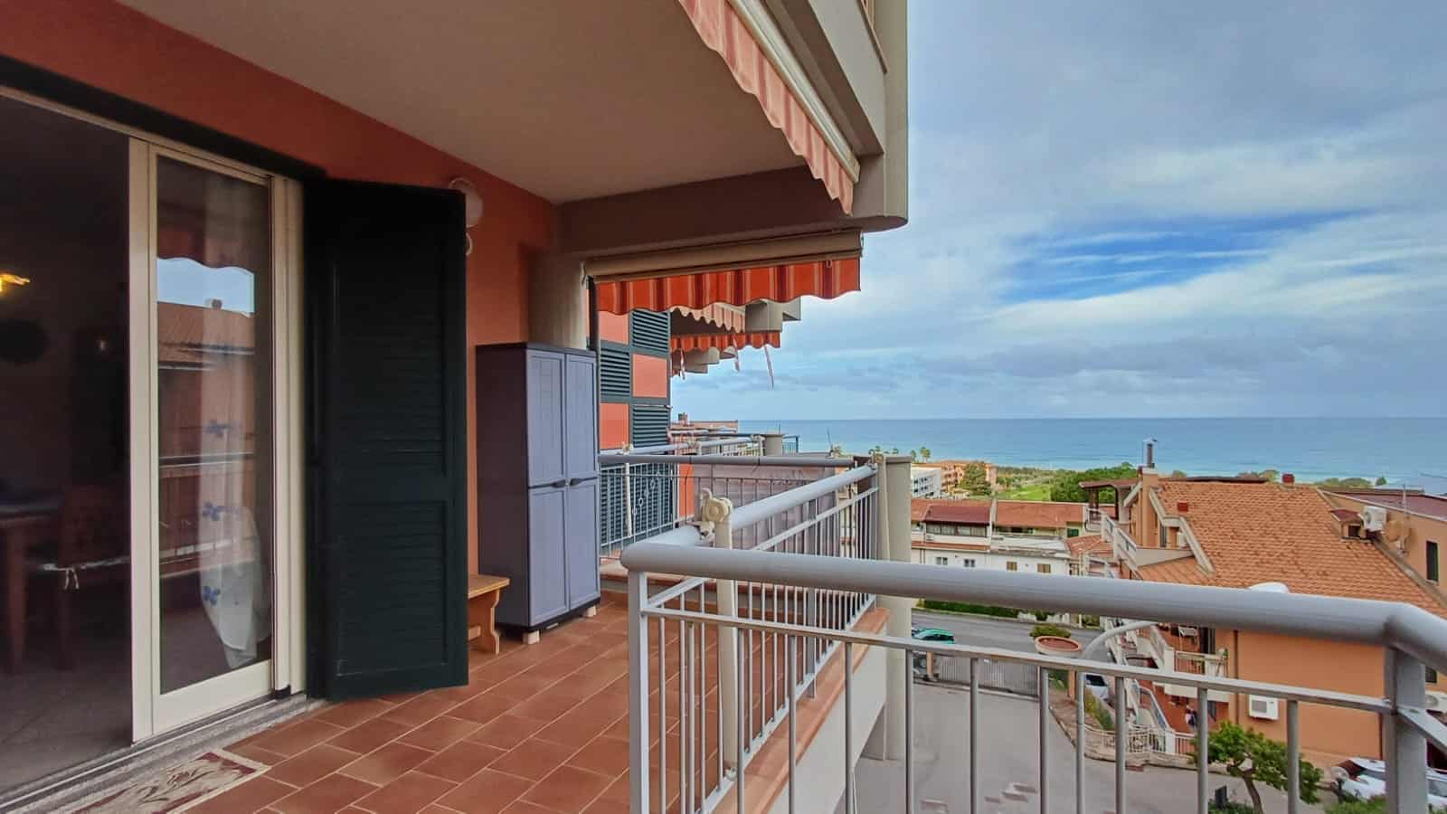 Vista panoramica mare dal balcone di un appartamento in affitto, vista mare, terrazzo con arredamento, vista città, case con tetti rossi, durante il giorno, scenario costiero italiana.
