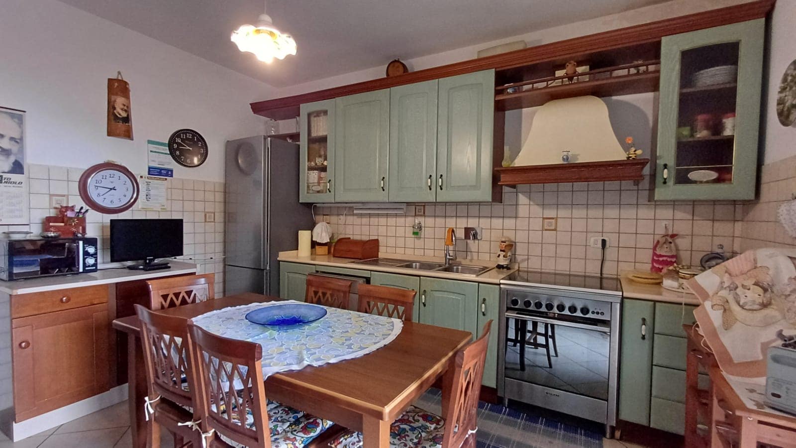 1. Cucina abitabile con mobili verdi, frigorifero e forno in una casa familiare accogliente e ben arredata.