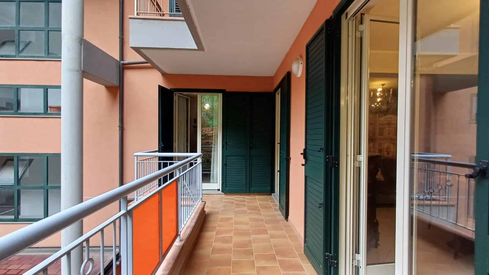 Balcone moderni con ringhiera in metallo, porte finestre con persiane verdi e vista su un edificio residenziale, ideale per appartamenti di nuova costruzione a Milano e zone limitrofe.