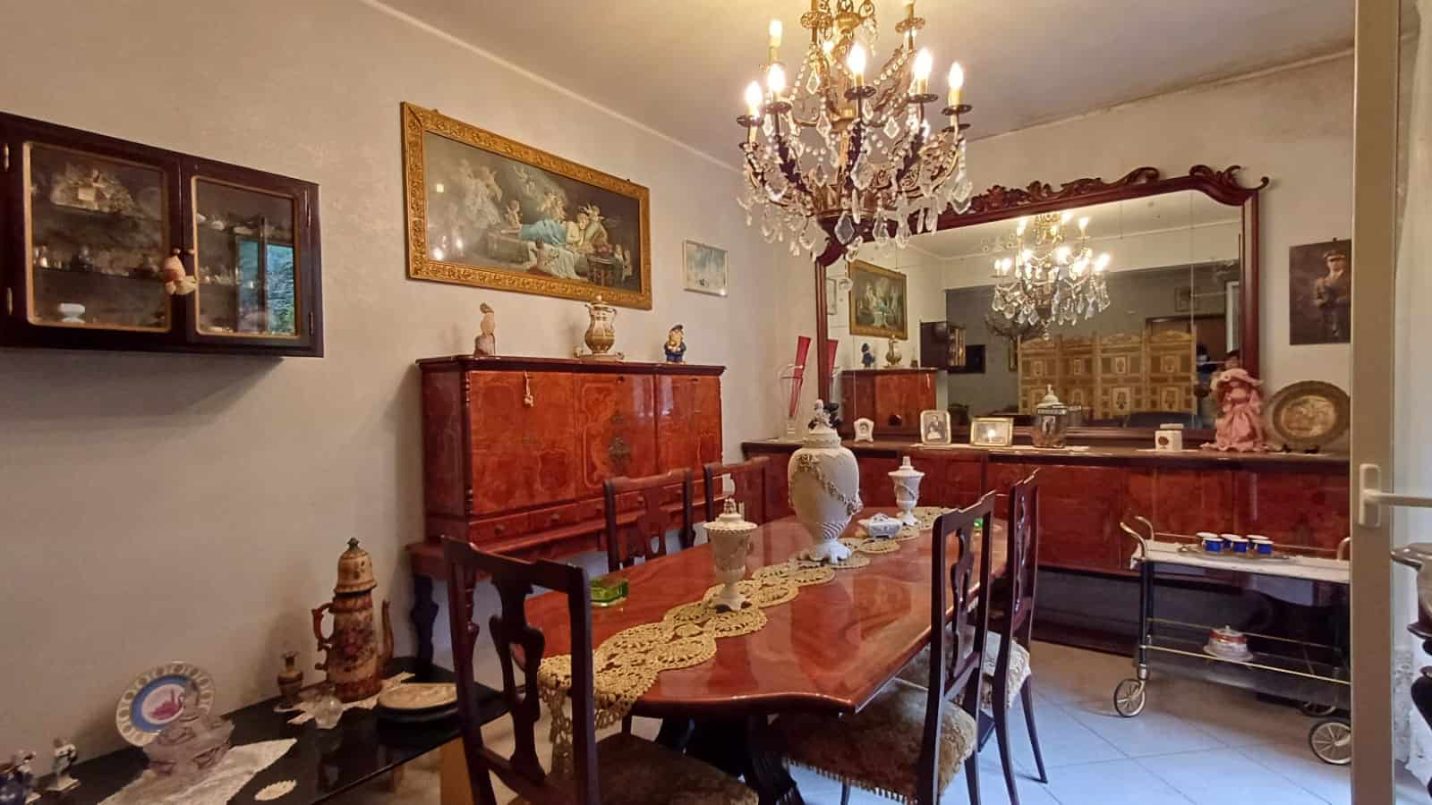 Elegante sala da pranzo con mobili in legno antico, lampadario chandeliers, decorazioni vintage, pareti decorate, ideale per case di charme e immobili di lusso.