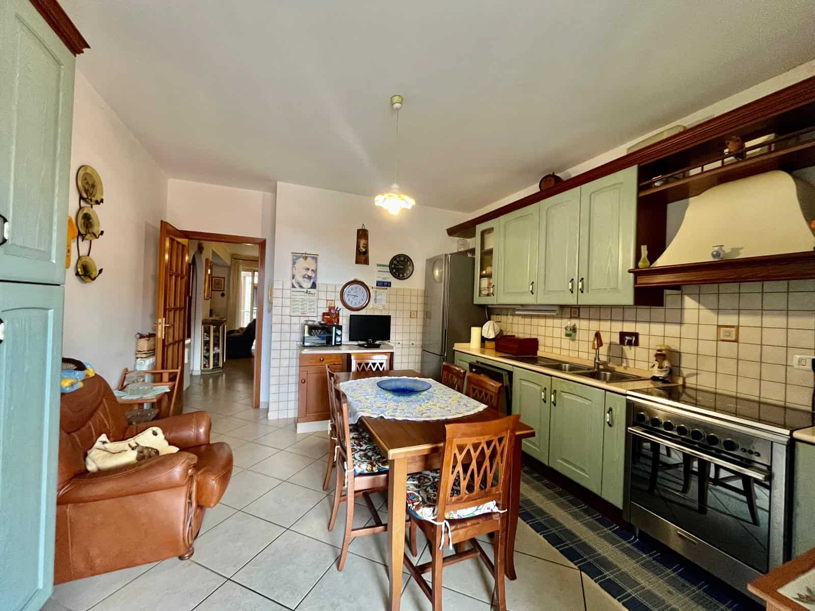 Spazioso soggiorno e cucina abitabile con mobili in stile country, pareti chiare, complementi in legno e dettagli decorativi per un ambiente accogliente in stile tradizionale italiano.