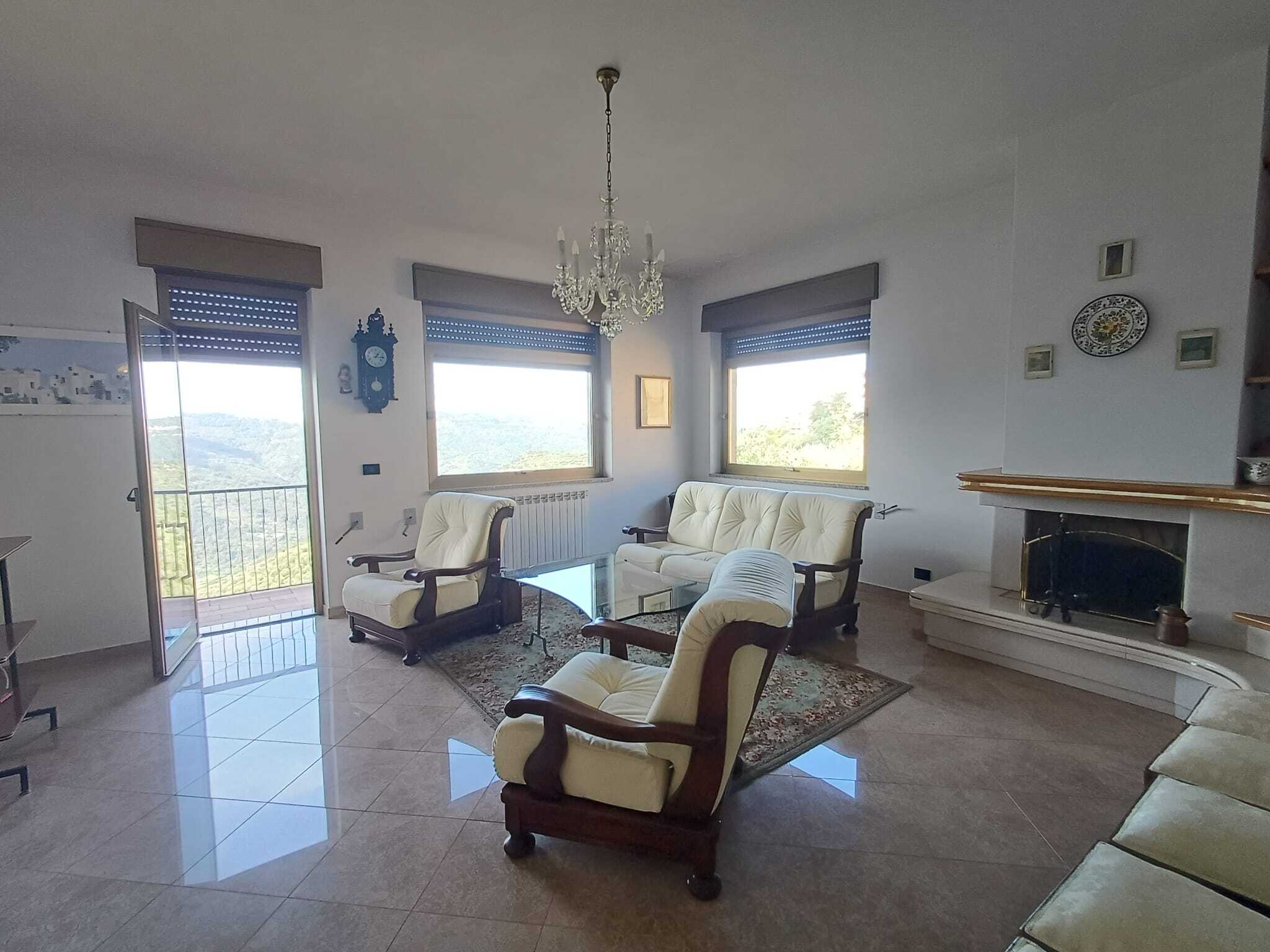 Accogliente soggiorno con divani antichi, camino e ampie finestre con vista panoramica, ideale per vivere ambienti eleganti e confortevoli in casa NextCasa.