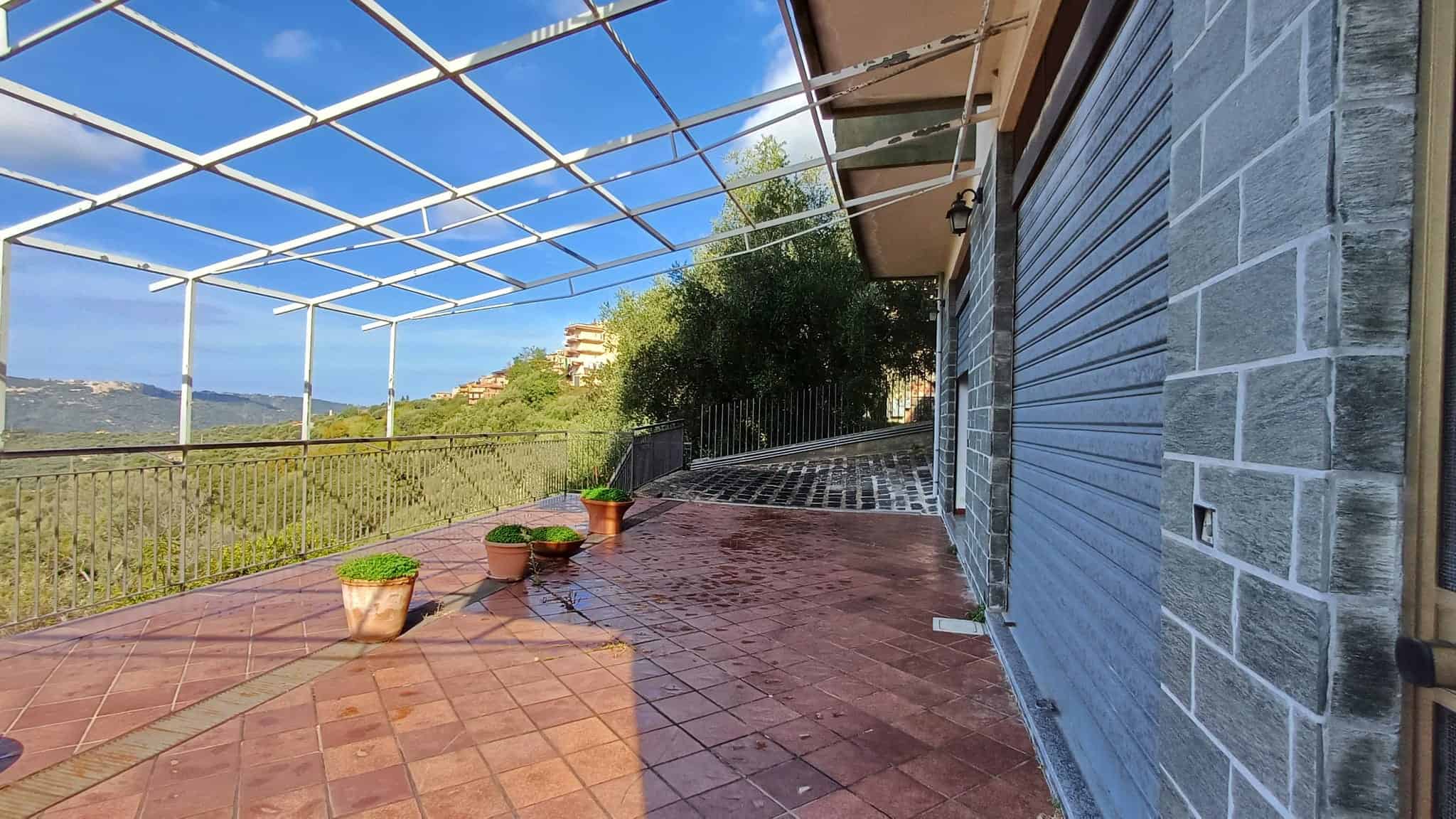 Veranda con vista panoramica e tettoia in metallo, pavimenti in cotto, piante in vaso, casa in pietra e legno, ampio spazio esterno, residenziale, ristrutturata, ambiente luminoso, relax, tranquillità, vista sul verde, proprietà NextCasa, immobili di qualità.